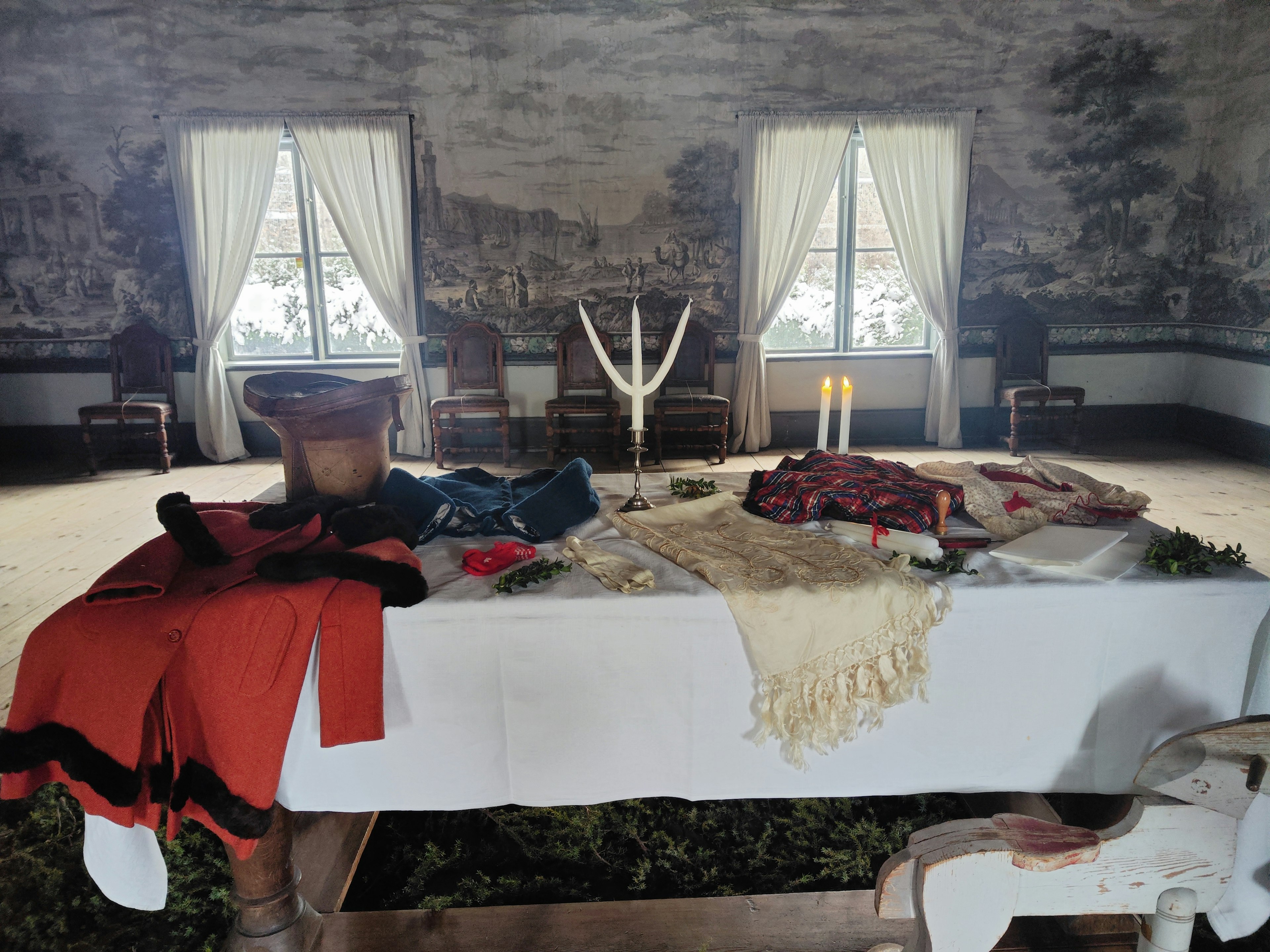 A large table in the center of a room with various fabrics and decorations displayed