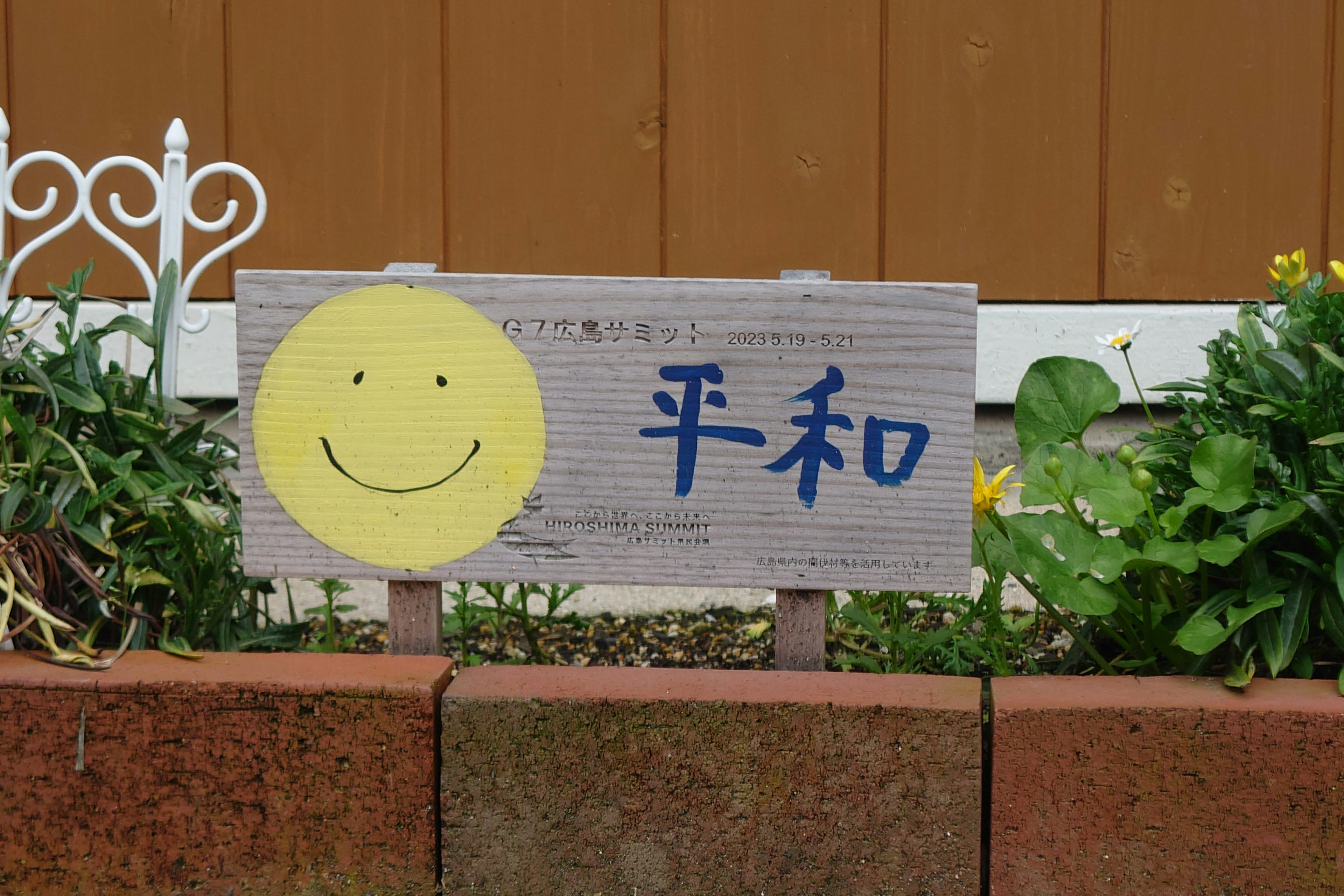 Eine Gartenszene mit einem Schild, das ein lächelndes Gesicht und das Wort Frieden auf Japanisch zeigt