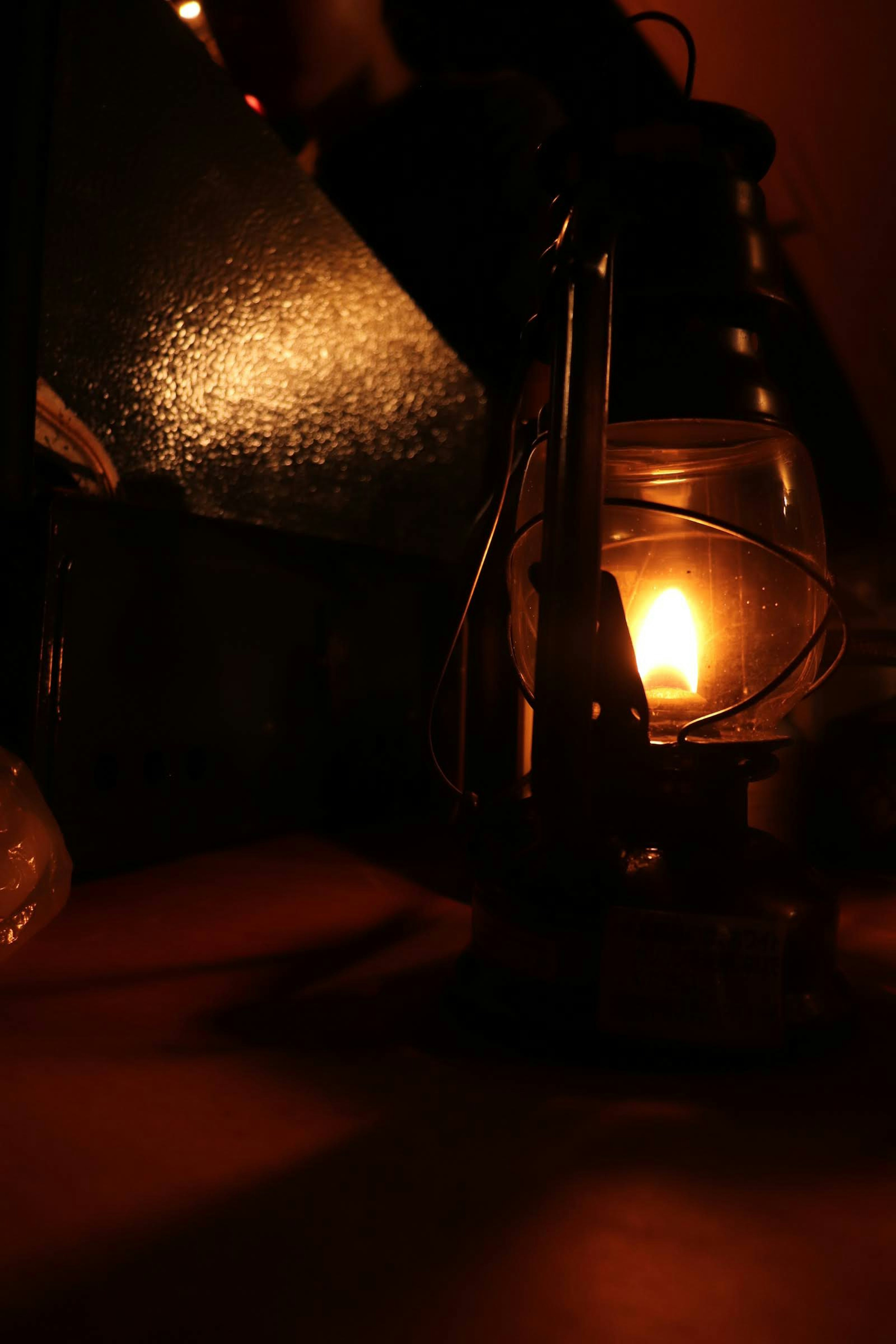 Close-up of an oil lamp emitting warm light and shadows