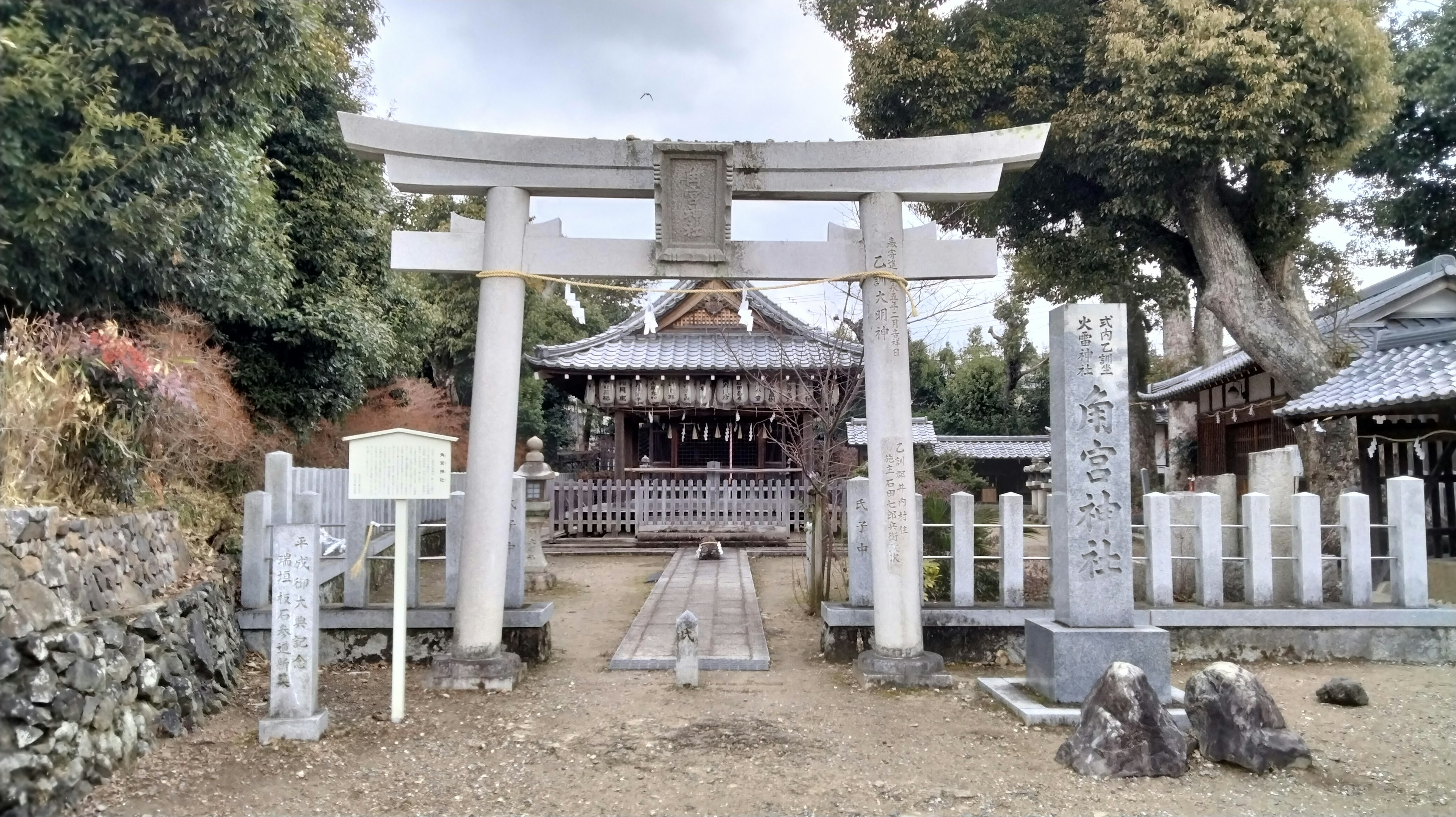 鳥居和神社被綠樹環繞，旁邊有石碑