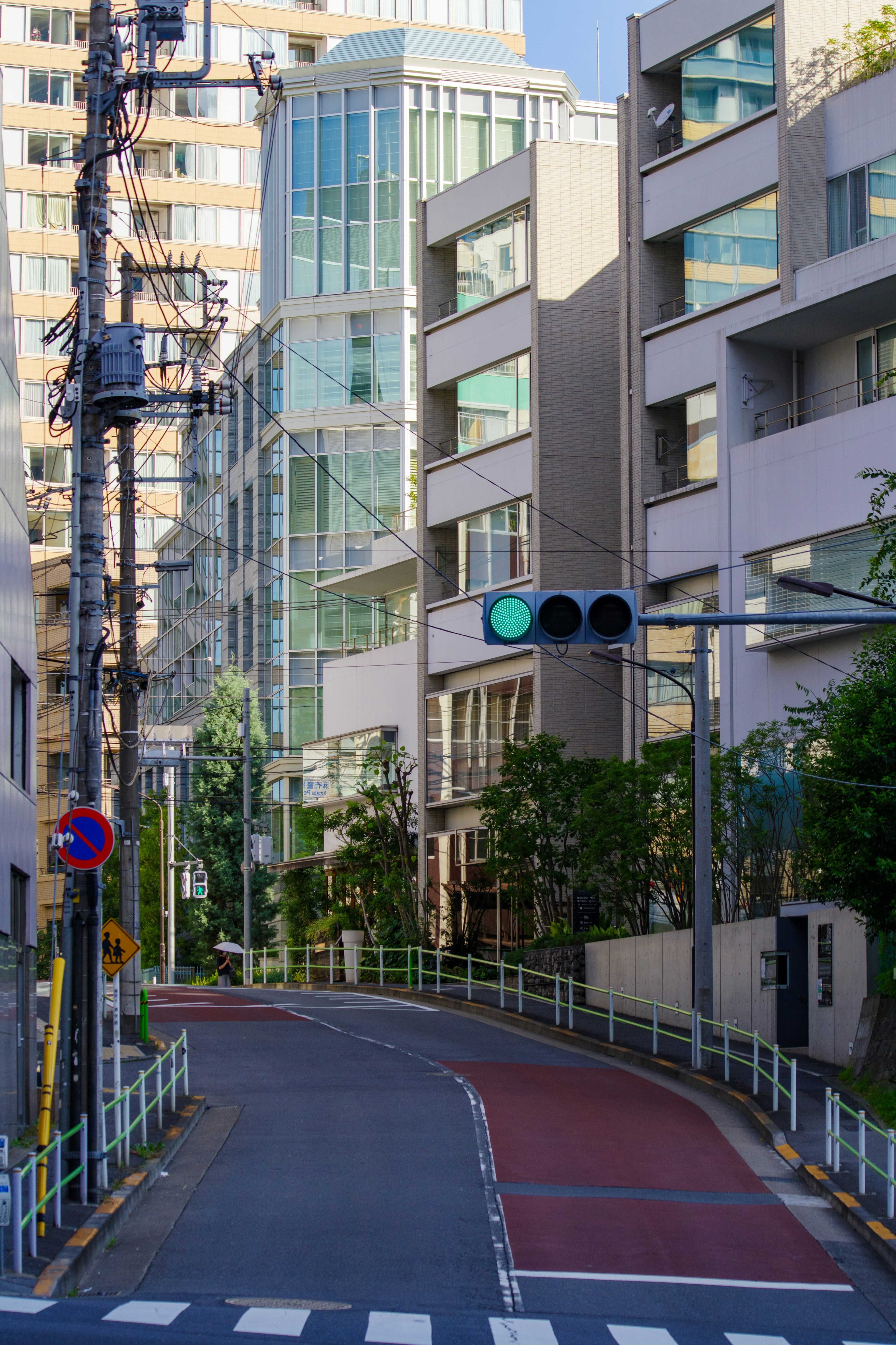 Modern buildings with greenery along a curved road featuring a traffic light