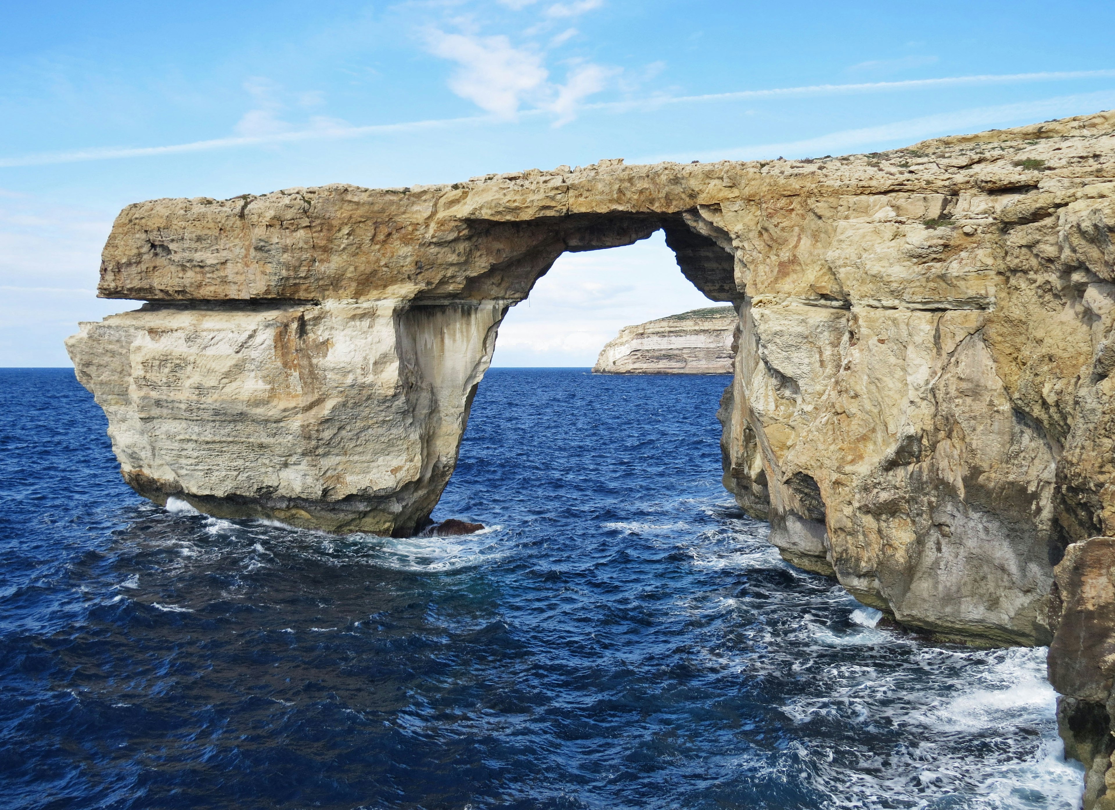 Natural rock arch over blue sea under clear sky