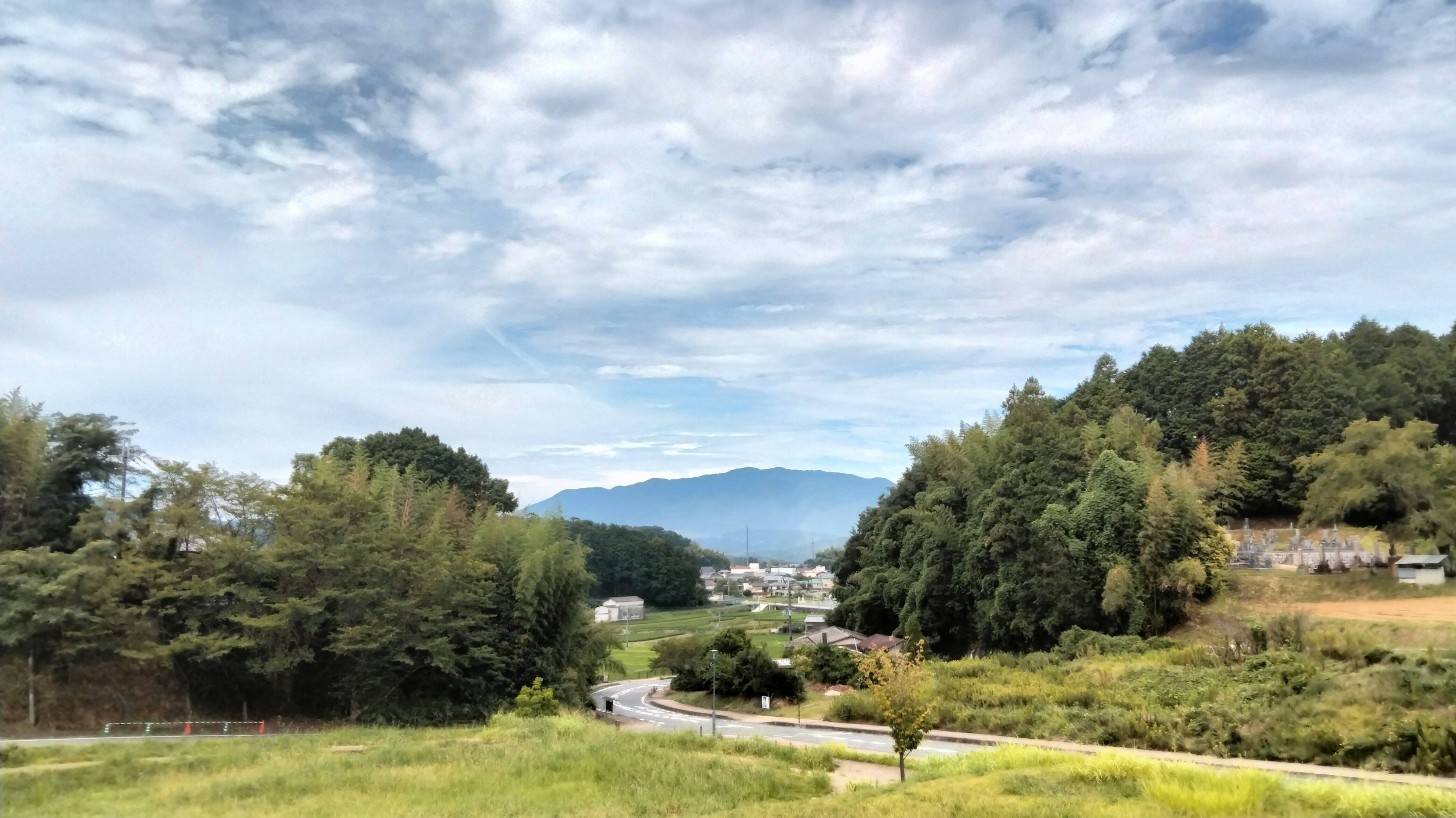 Scenic landscape with blue sky and clouds featuring mountains and a village