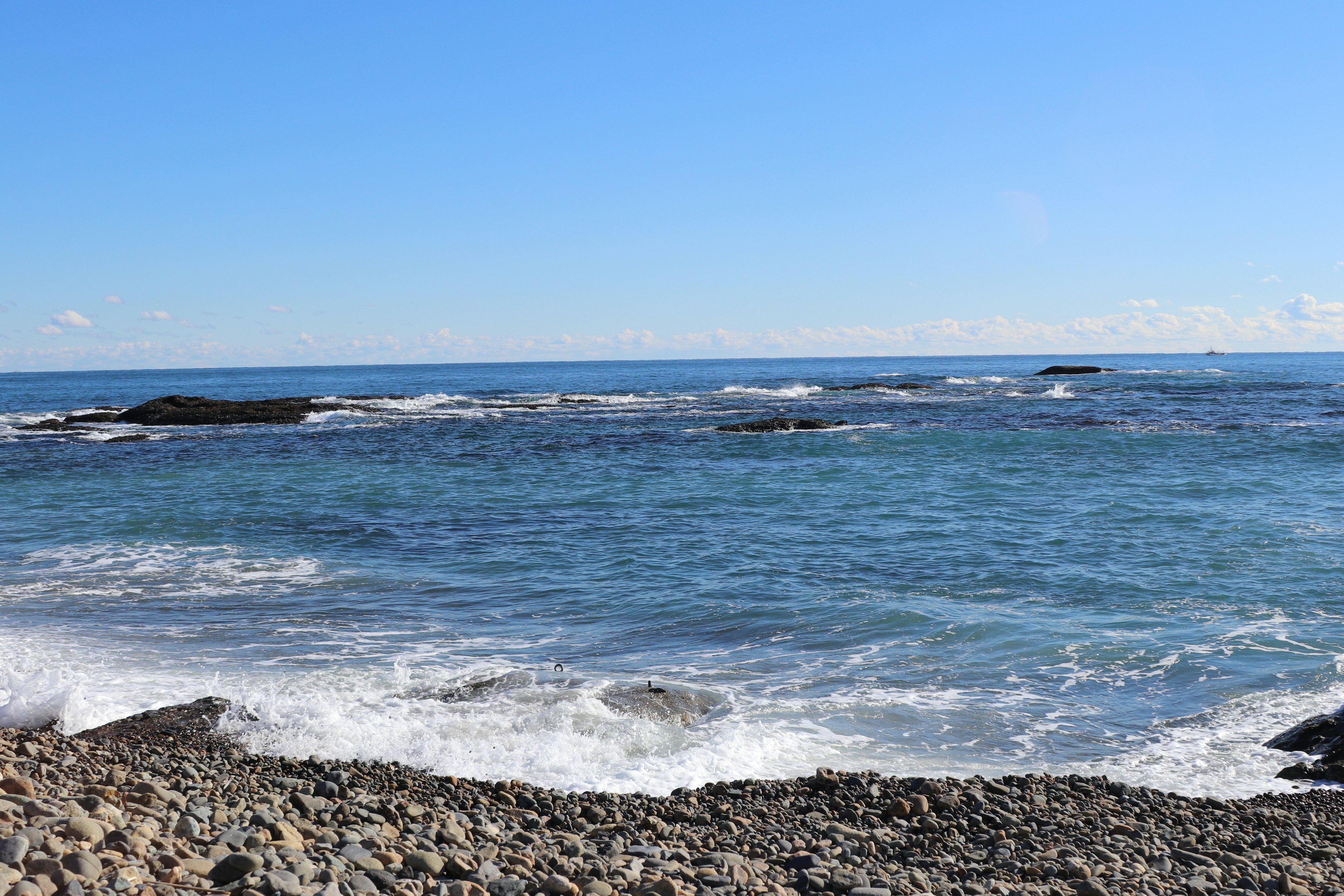 Scenic view of blue ocean waves crashing on rocky shore