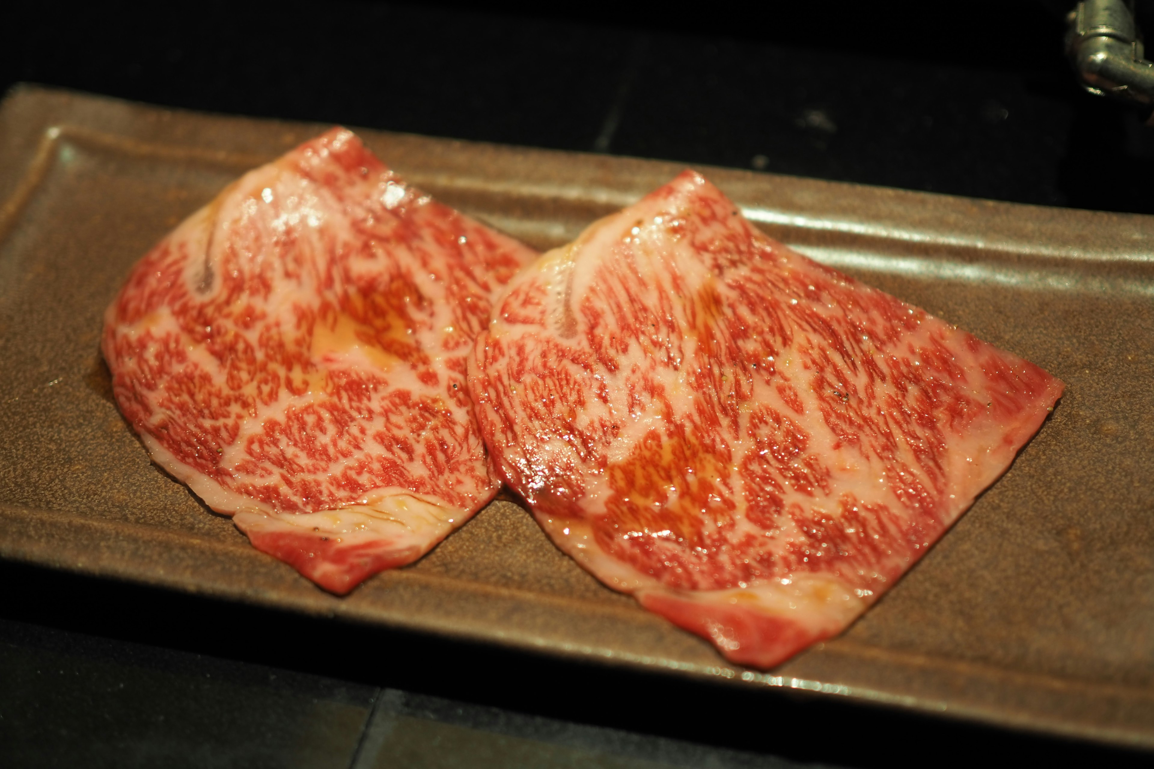 Irisan daging wagyu yang bermarmar cantik di atas piring