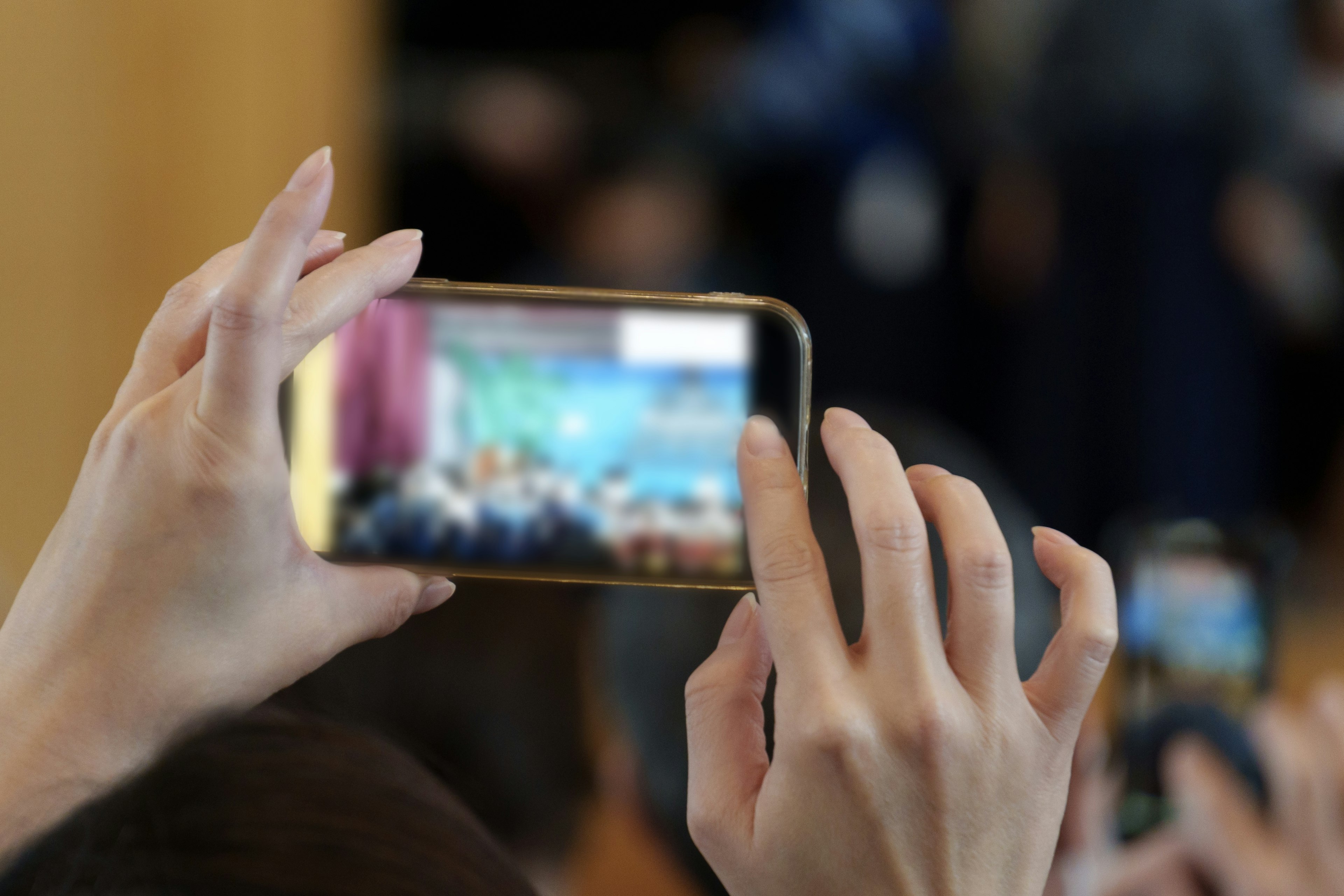 A hand holding a smartphone capturing an event