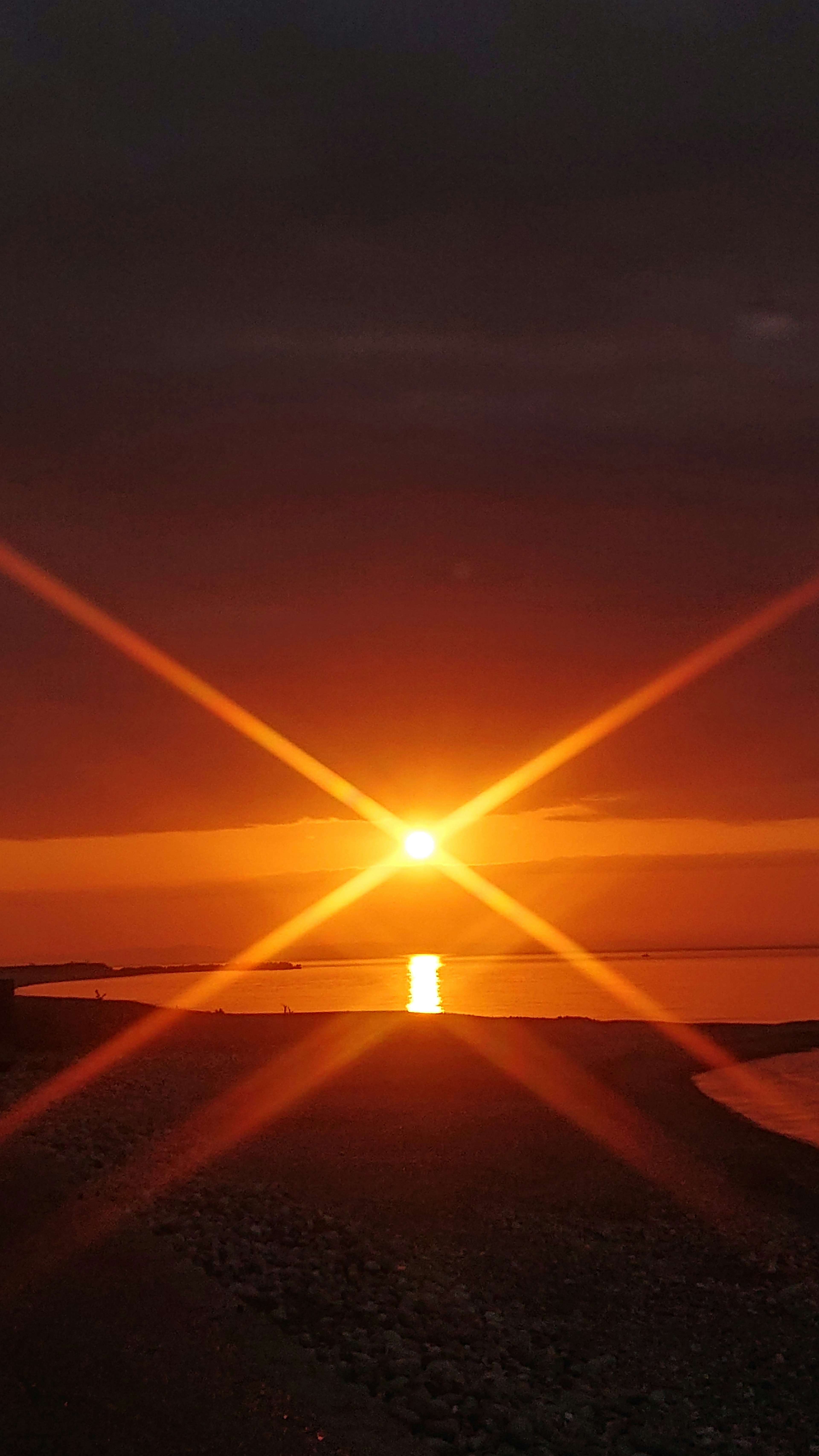 Sunset over the ocean with star-shaped light reflections