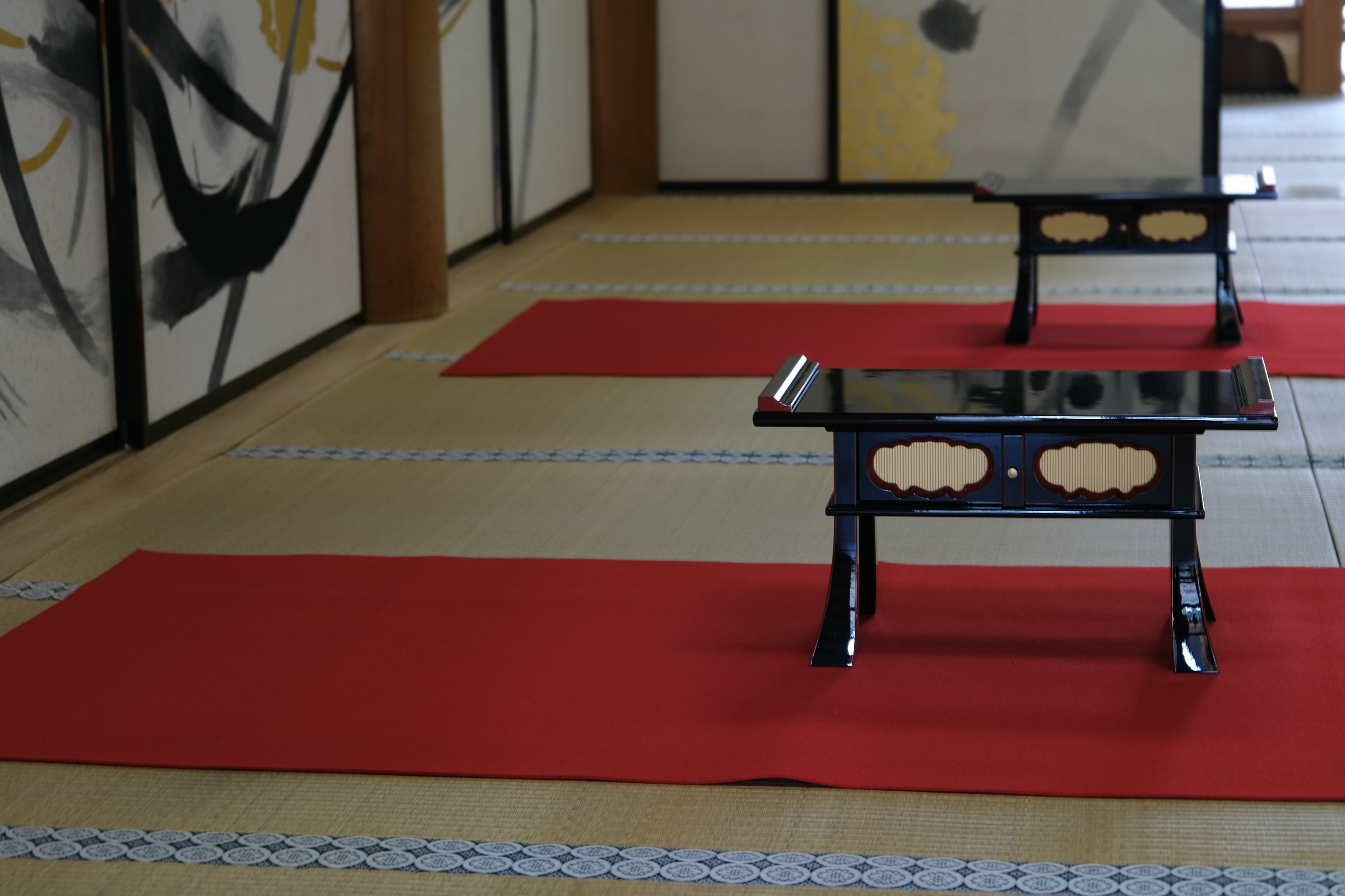 Interior de una habitación japonesa con mesas negras sobre alfombras rojas