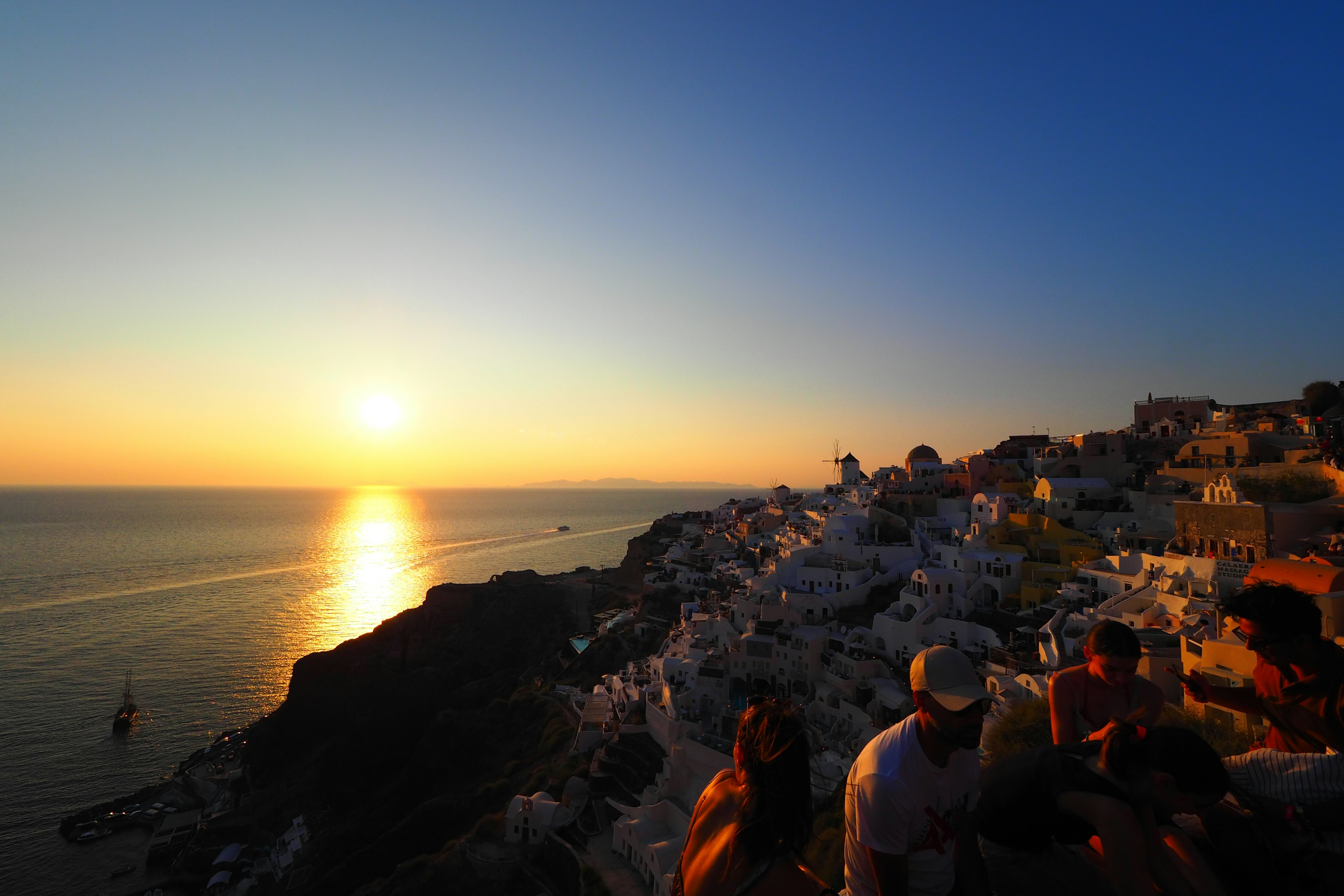 Raggruppamento di turisti con il tramonto di Santorini sullo sfondo