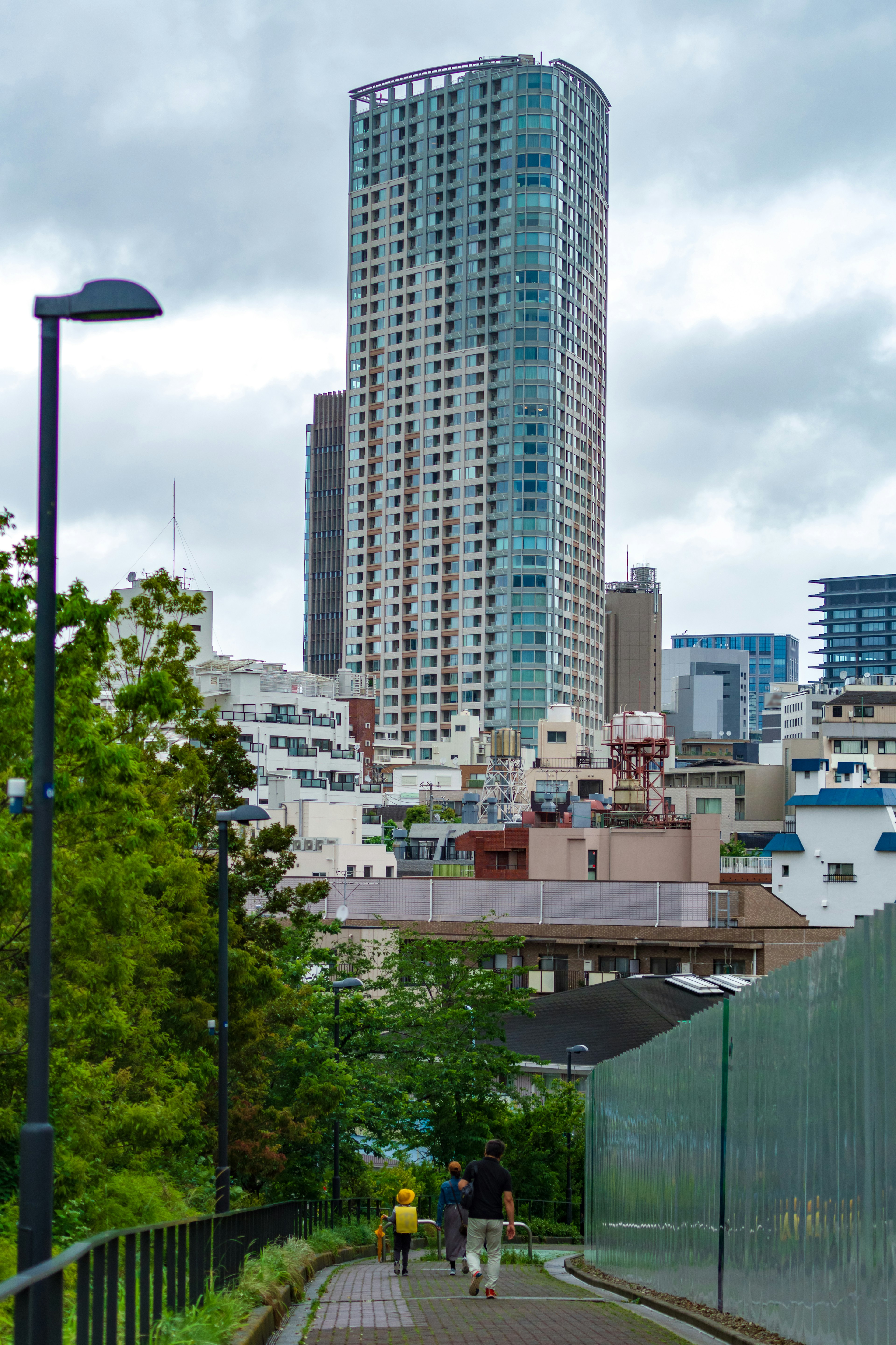 Cityscape featuring a tall building with people walking along a green path