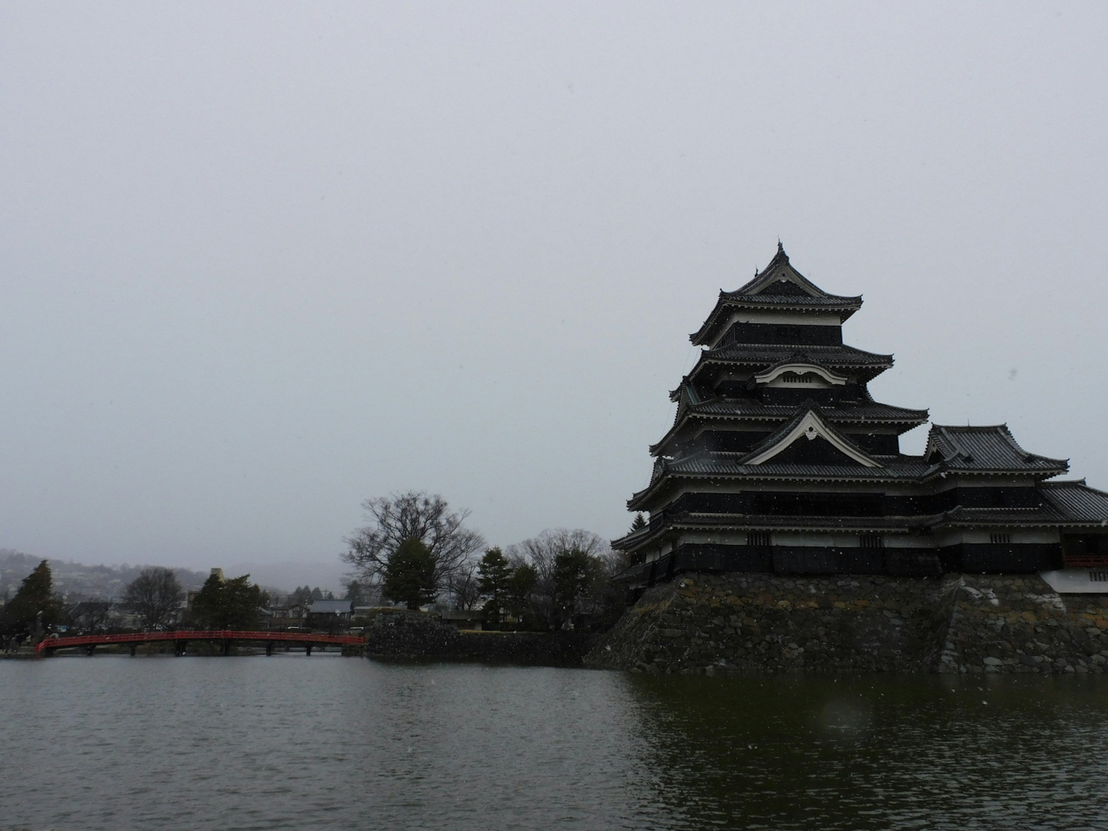 Kastil Matsumoto dalam pemandangan musim dingin di tepi danau dengan struktur hitam dan salju di sekitarnya