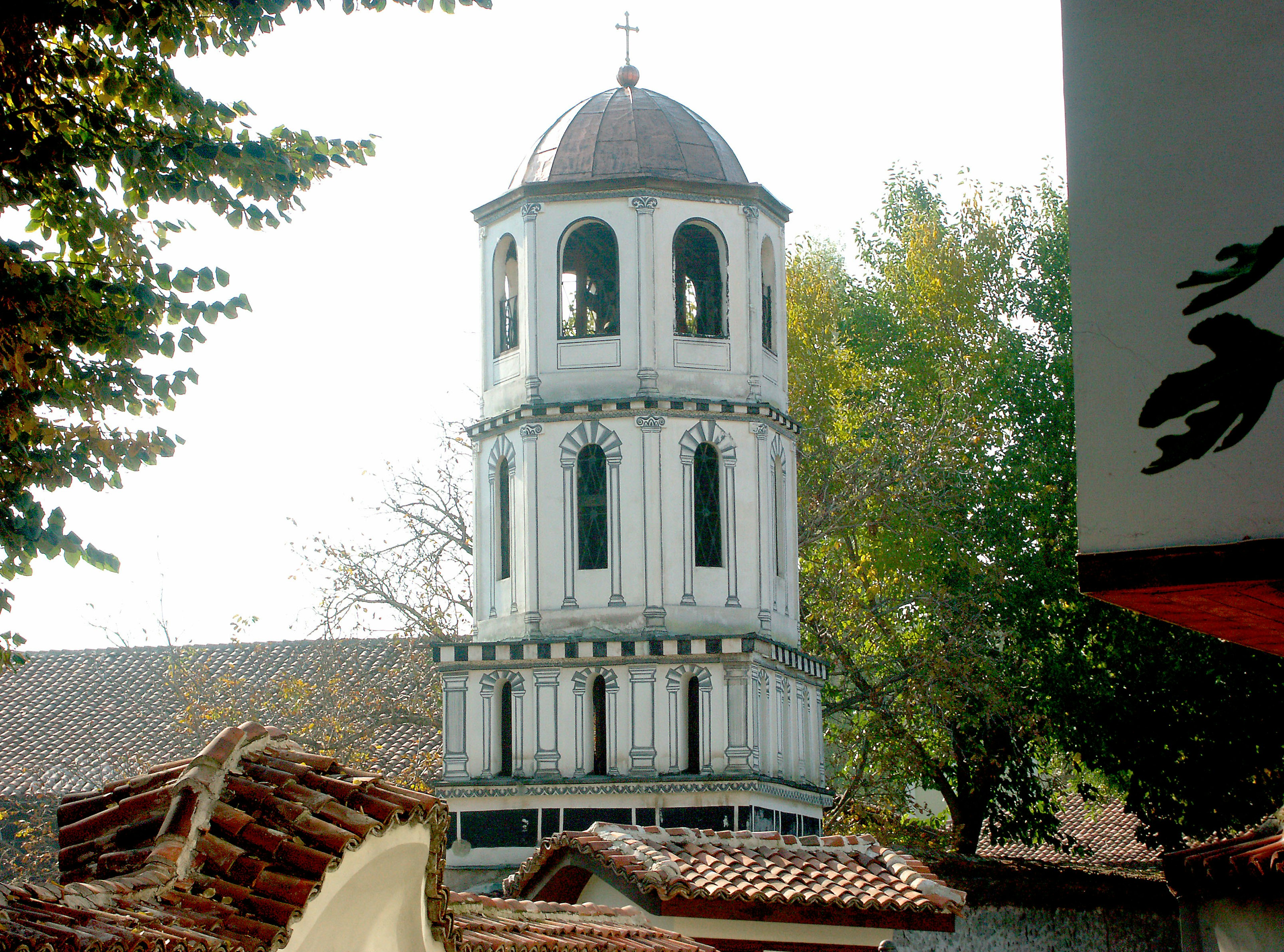 Immagine di una torre campanaria bianca circondata da alberi verdi