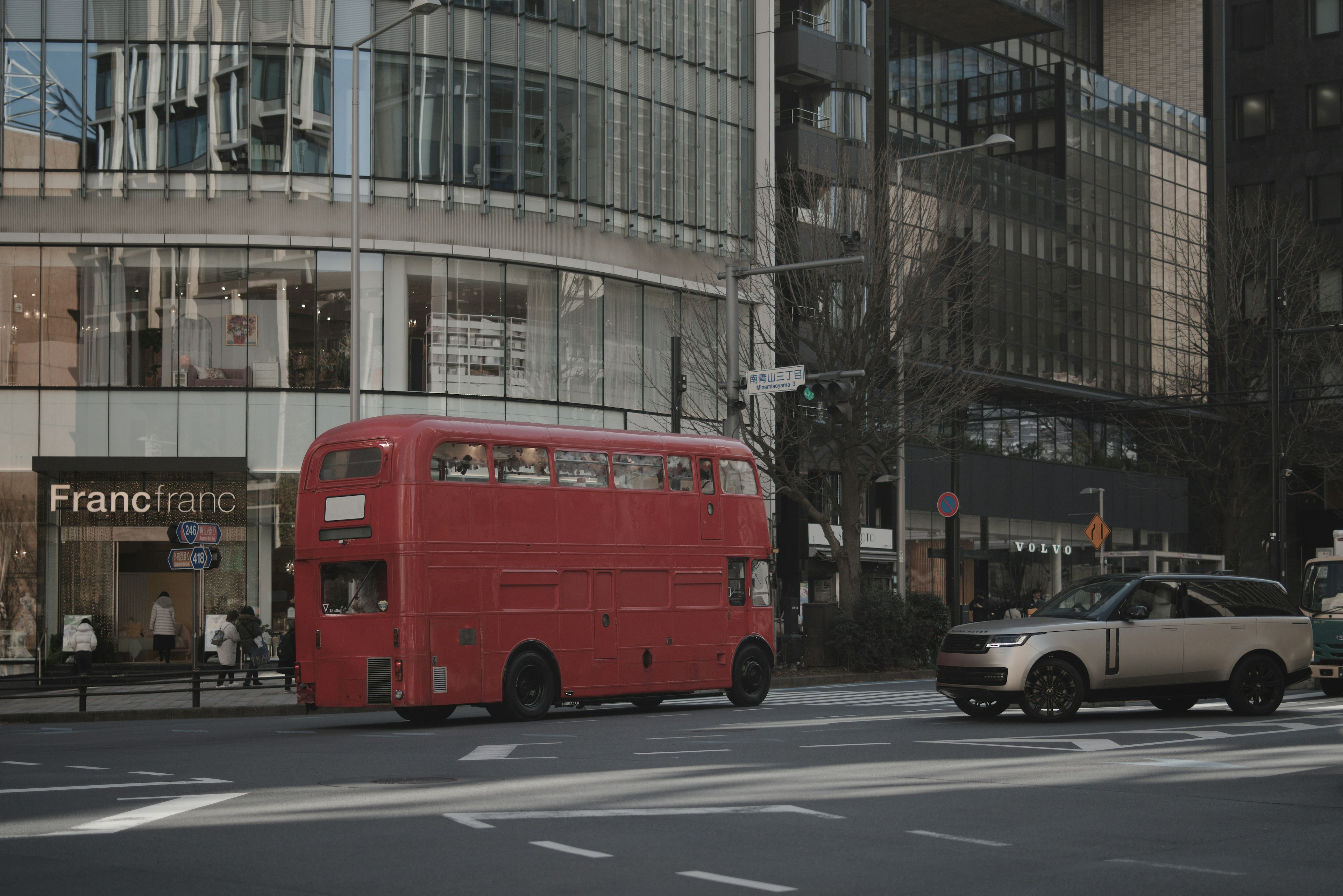 Red double-decker bus passing by a modern building