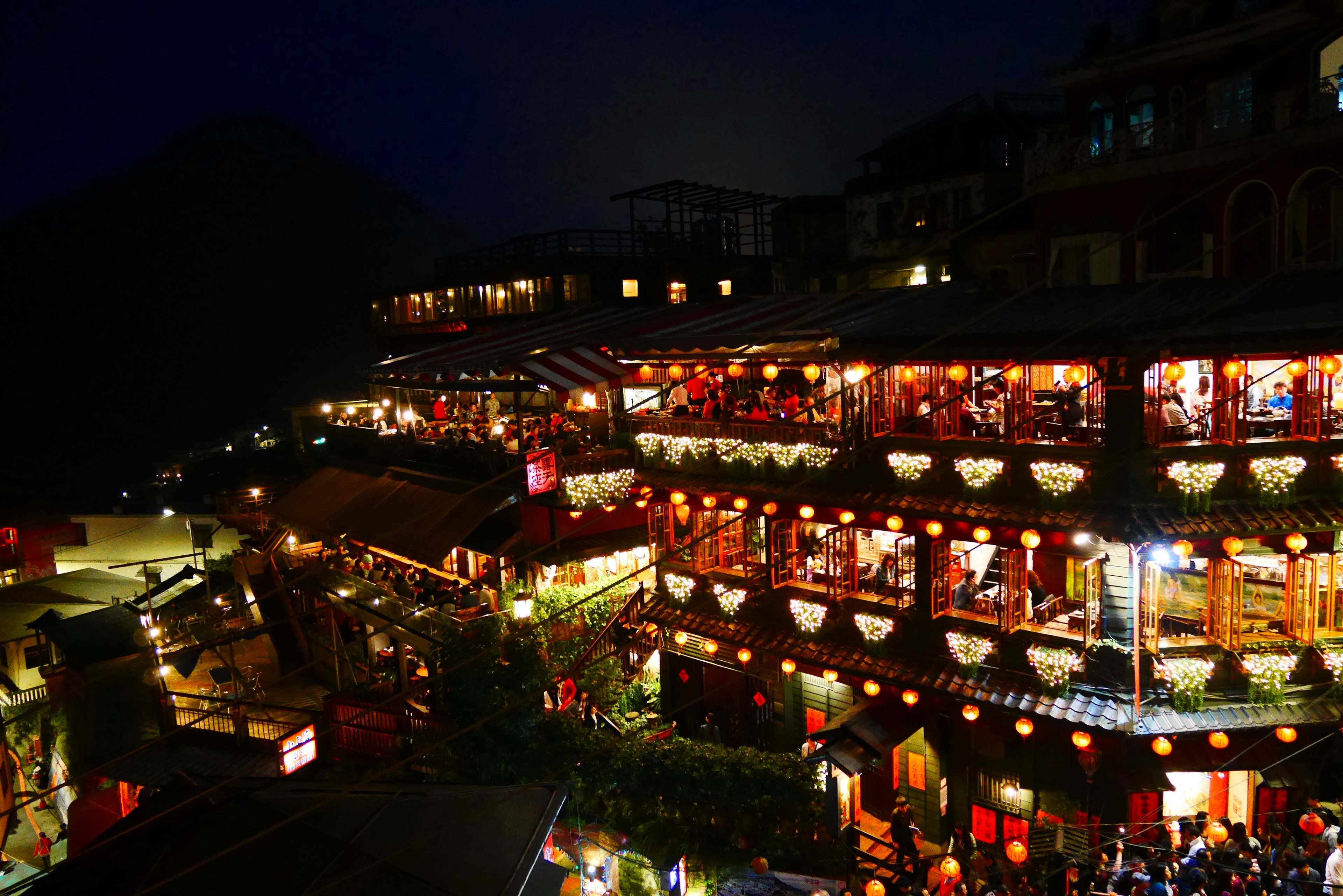 Vista nocturna del pueblo de Jiufen con tiendas iluminadas y faroles