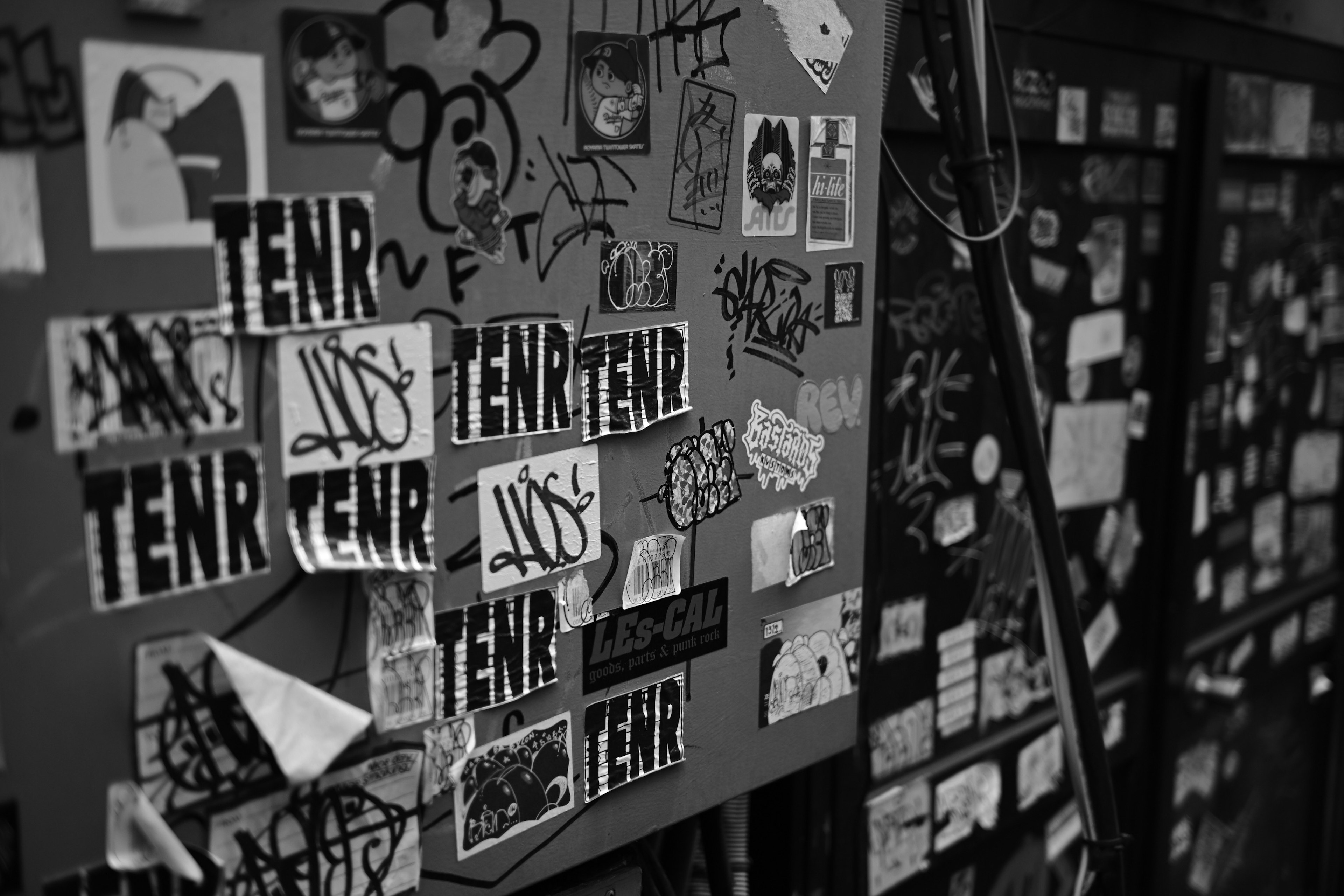 Una colección de varios stickers y grafitis en una pared en blanco y negro