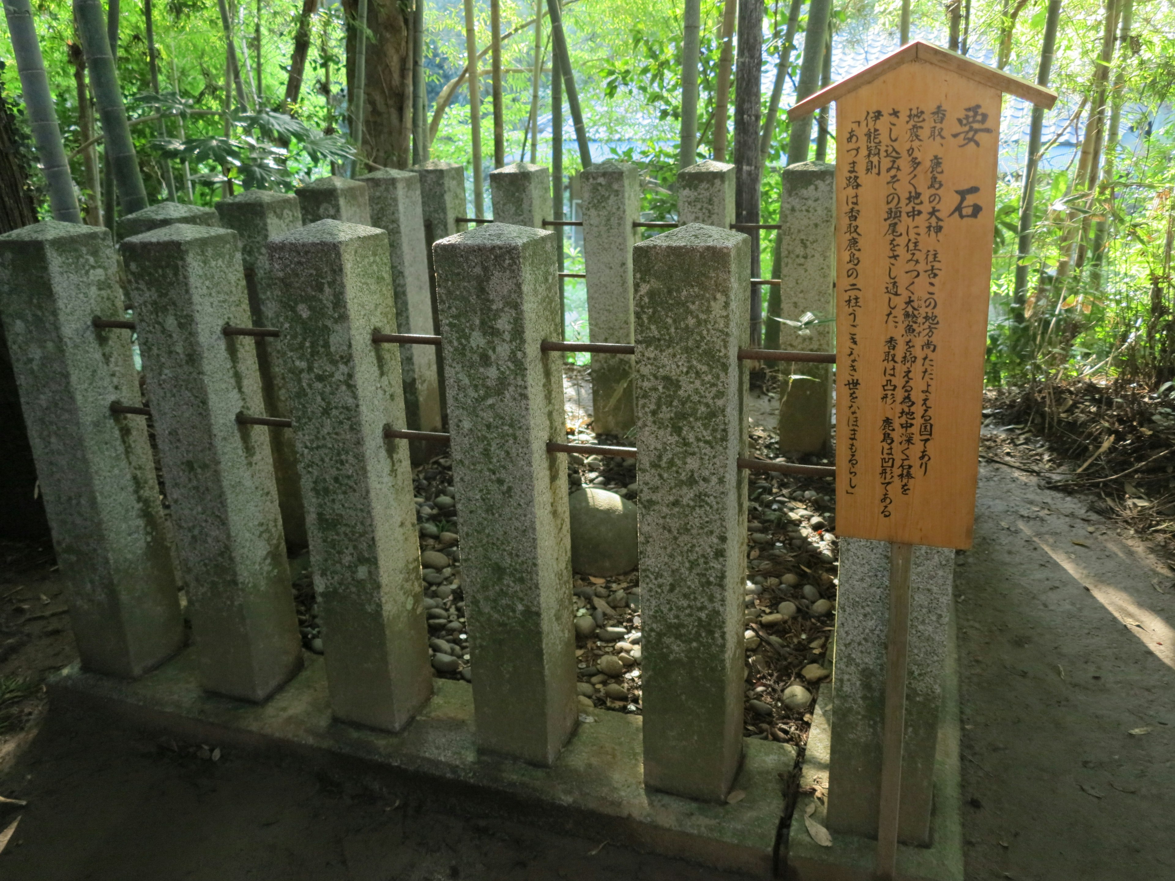 竹林の中にある石柱と説明看板のある風景