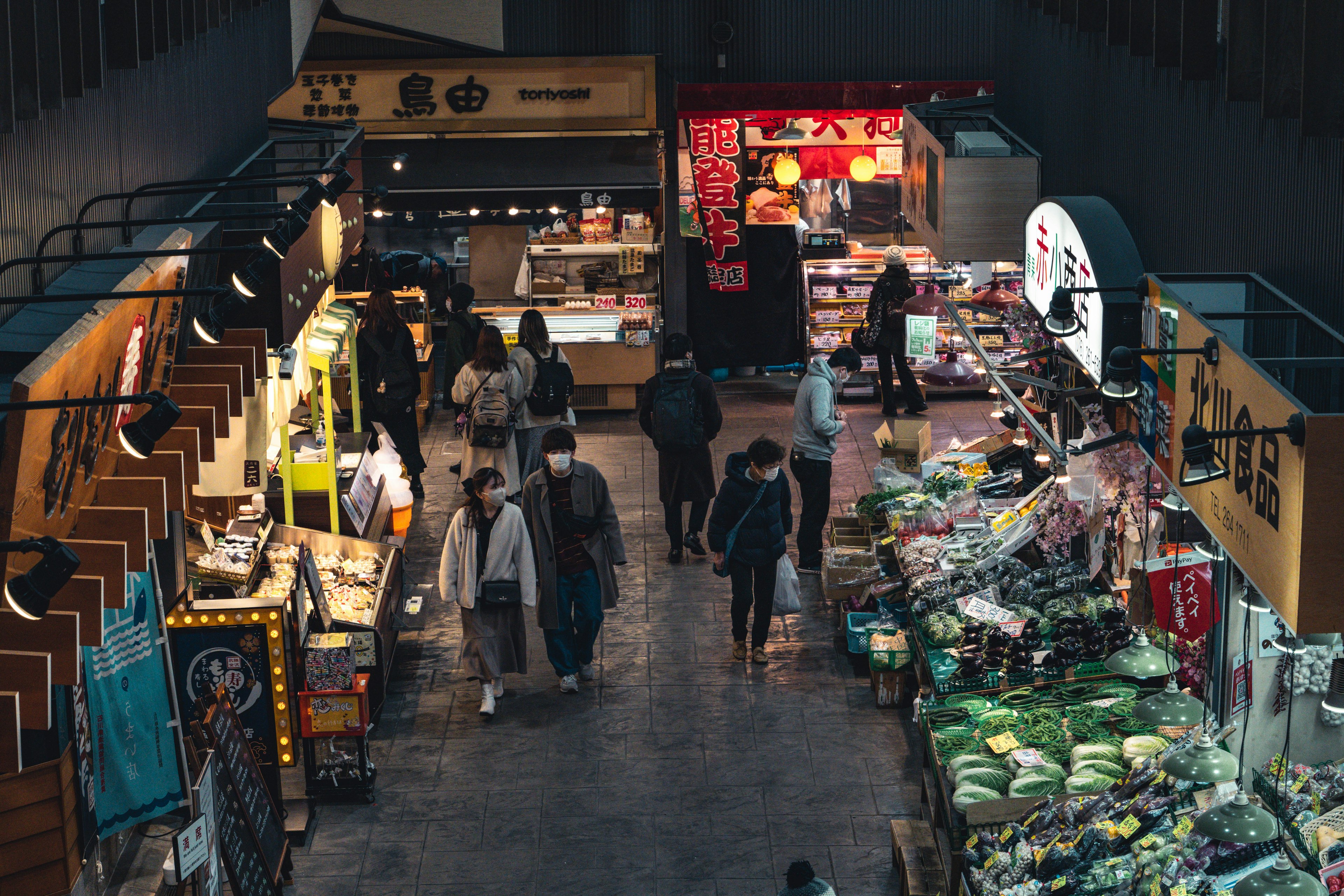 Aerial view of an indoor market featuring various food stalls and shoppers walking through