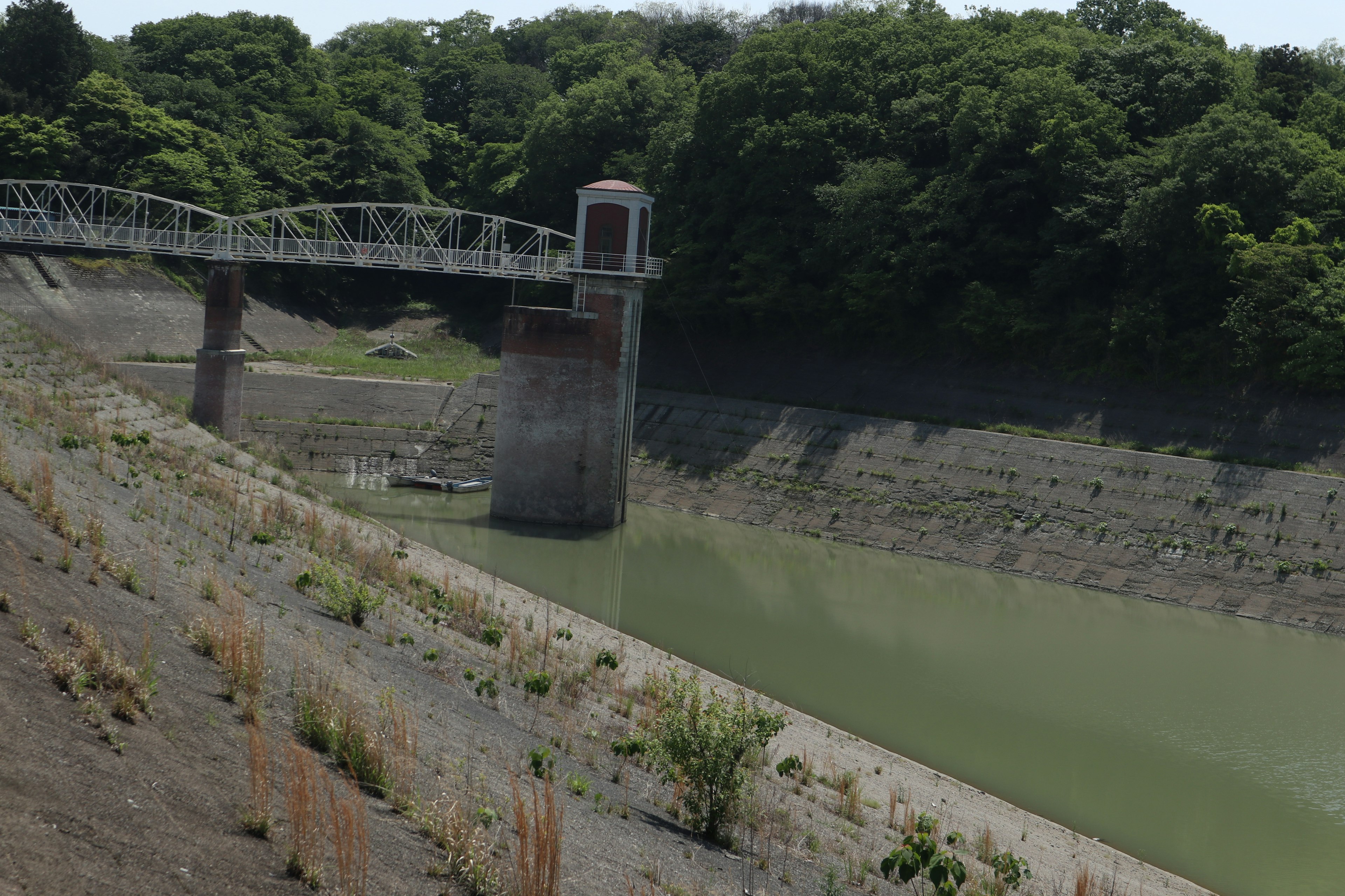 Réservoir asséché avec un pont et un arrière-plan verdoyant