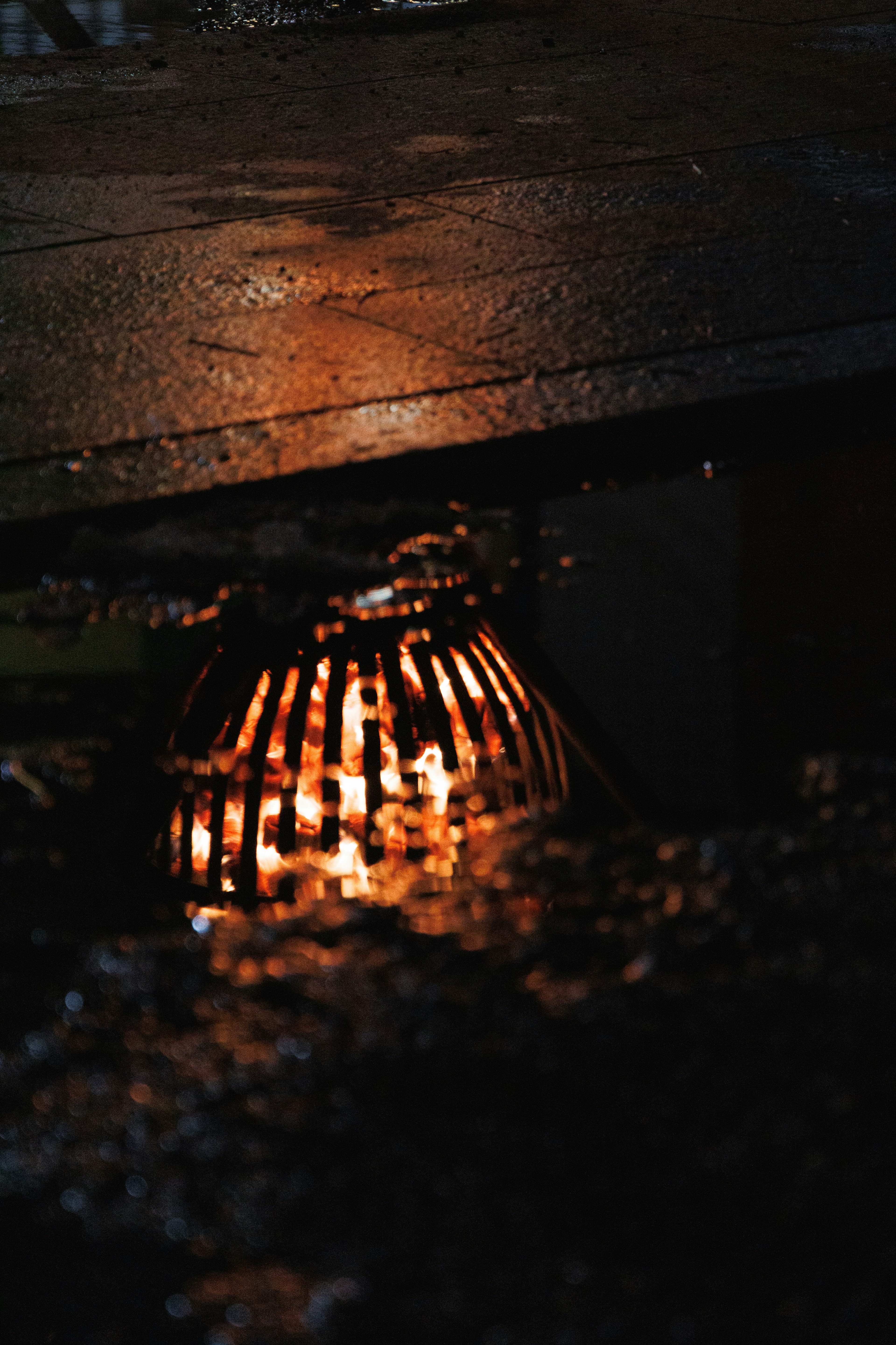 Light reflecting from a manhole cover in a puddle on a wet surface