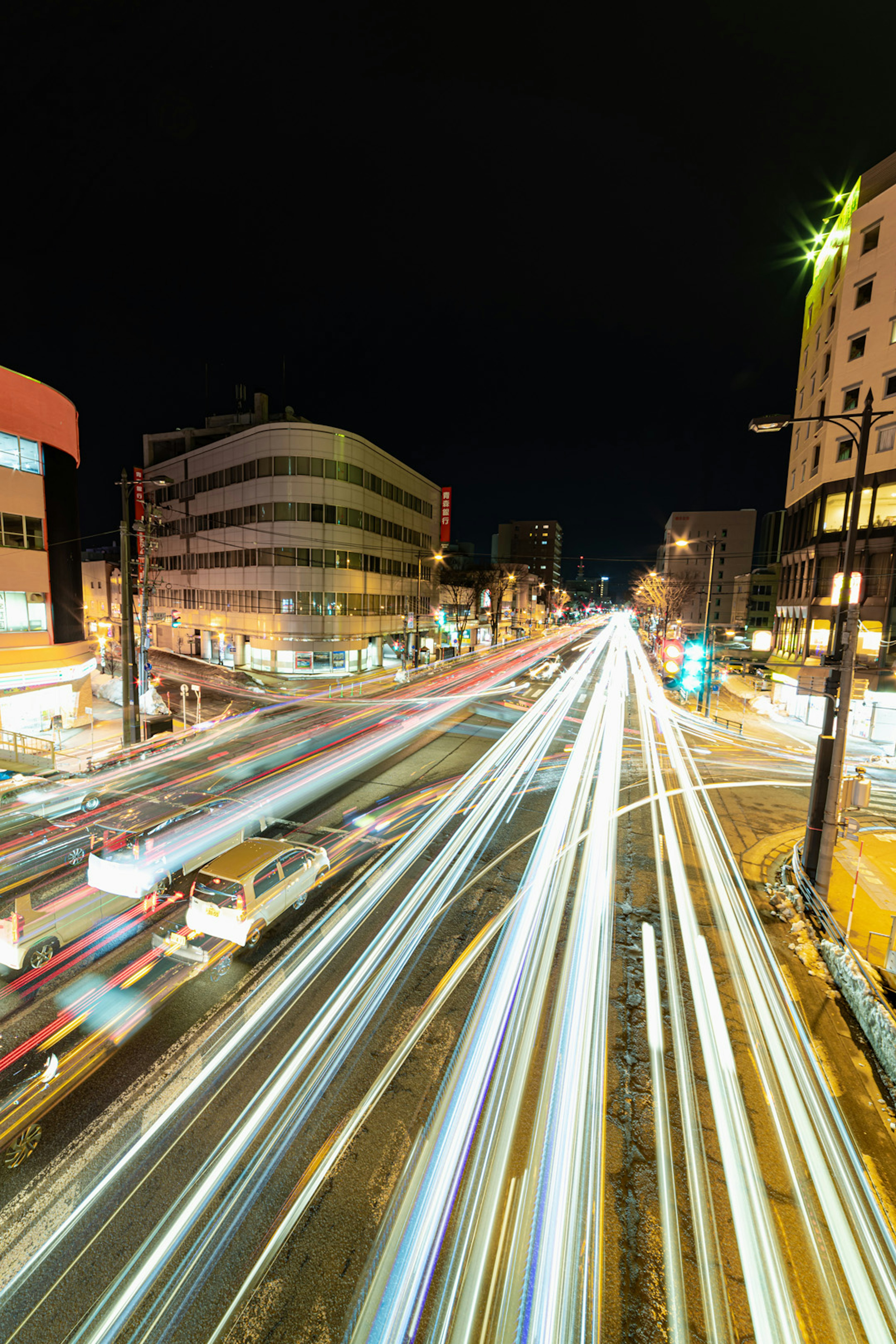 Traînées de lumière de circulation à un carrefour urbain la nuit