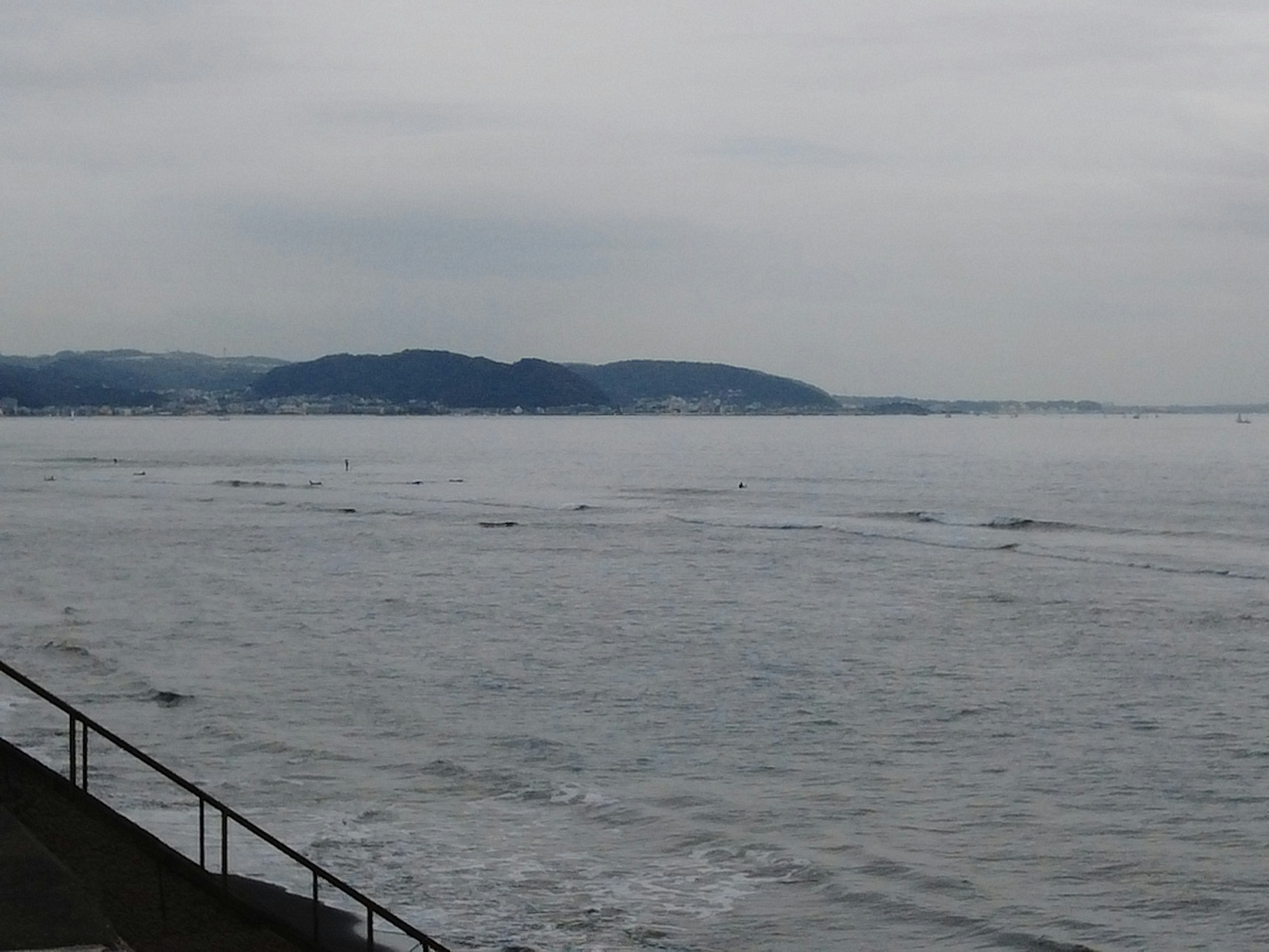 穏やかな海と曇り空の風景 沿岸には山々が広がり 静かな水面が映える