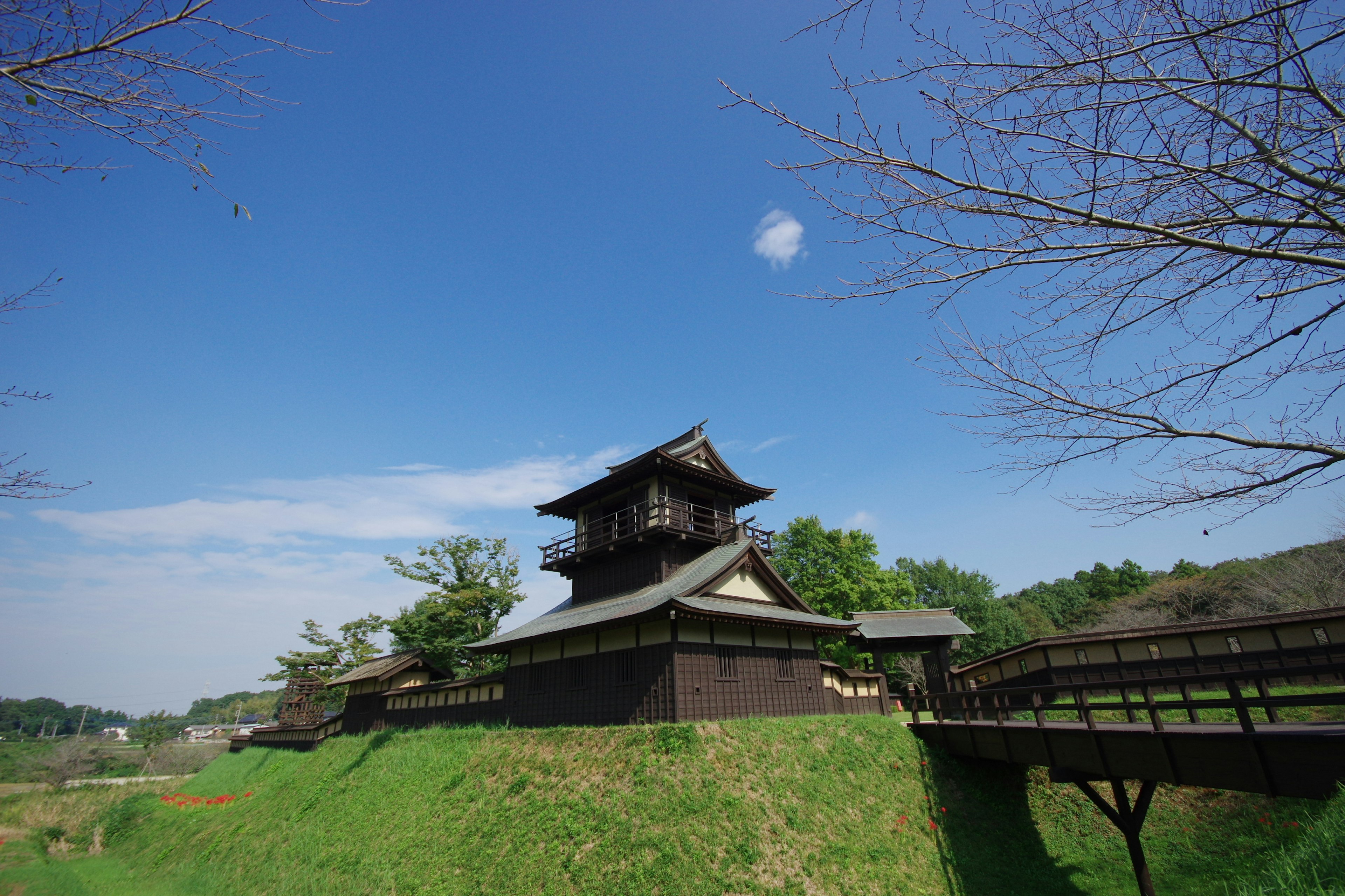 Bangunan kastil Jepang tradisional di atas bukit hijau di bawah langit biru