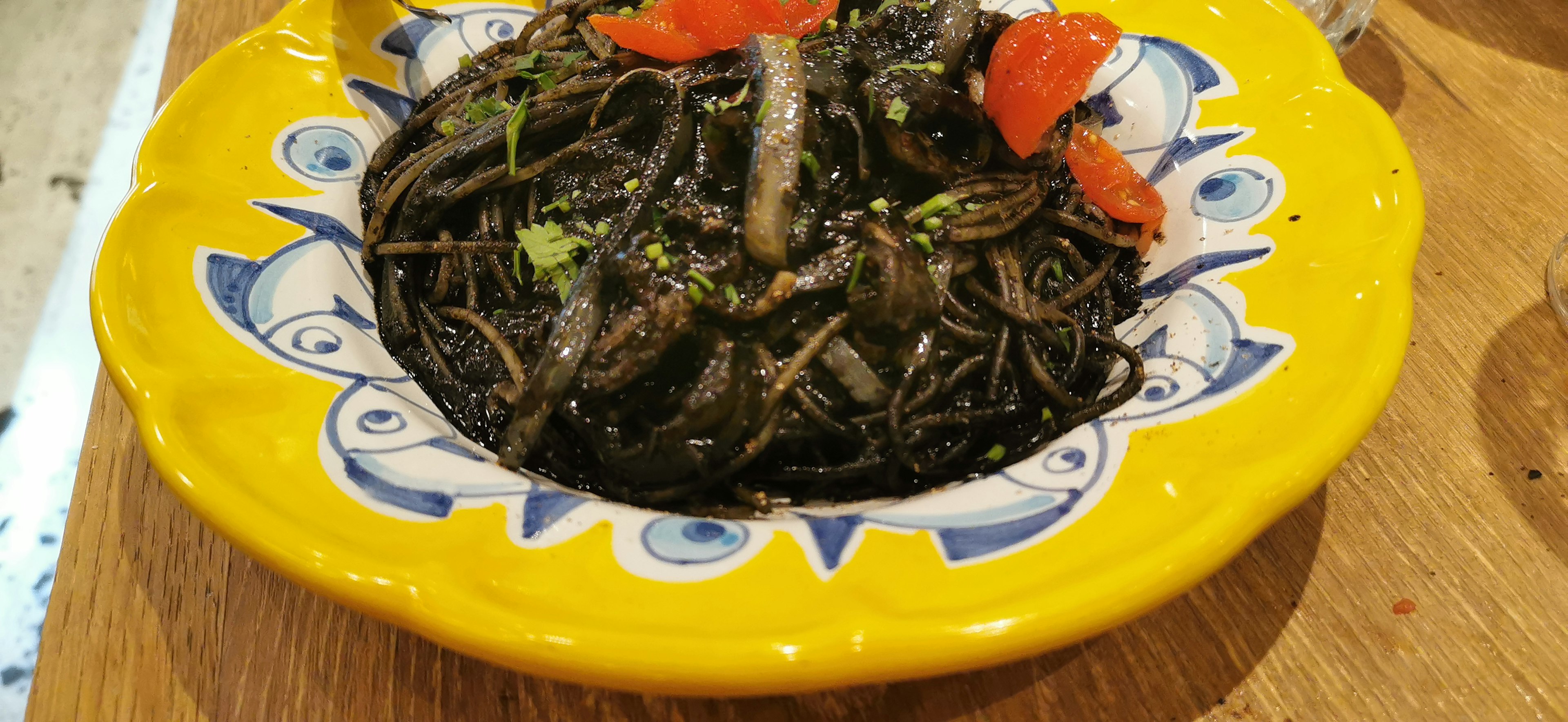 Seaweed dish served in a yellow plate with red tomato topping