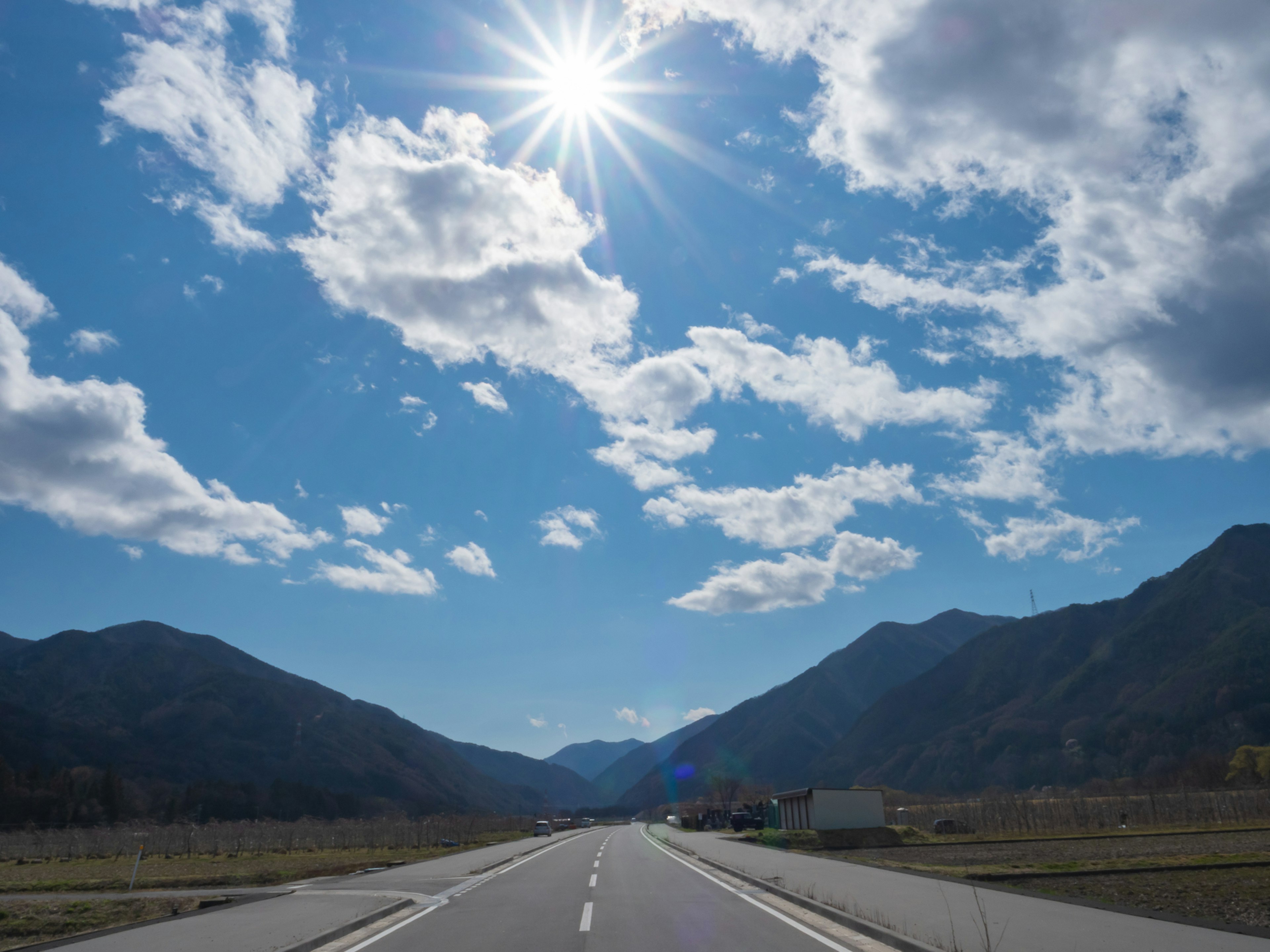 Bergstraße mit blauem Himmel und Wolken