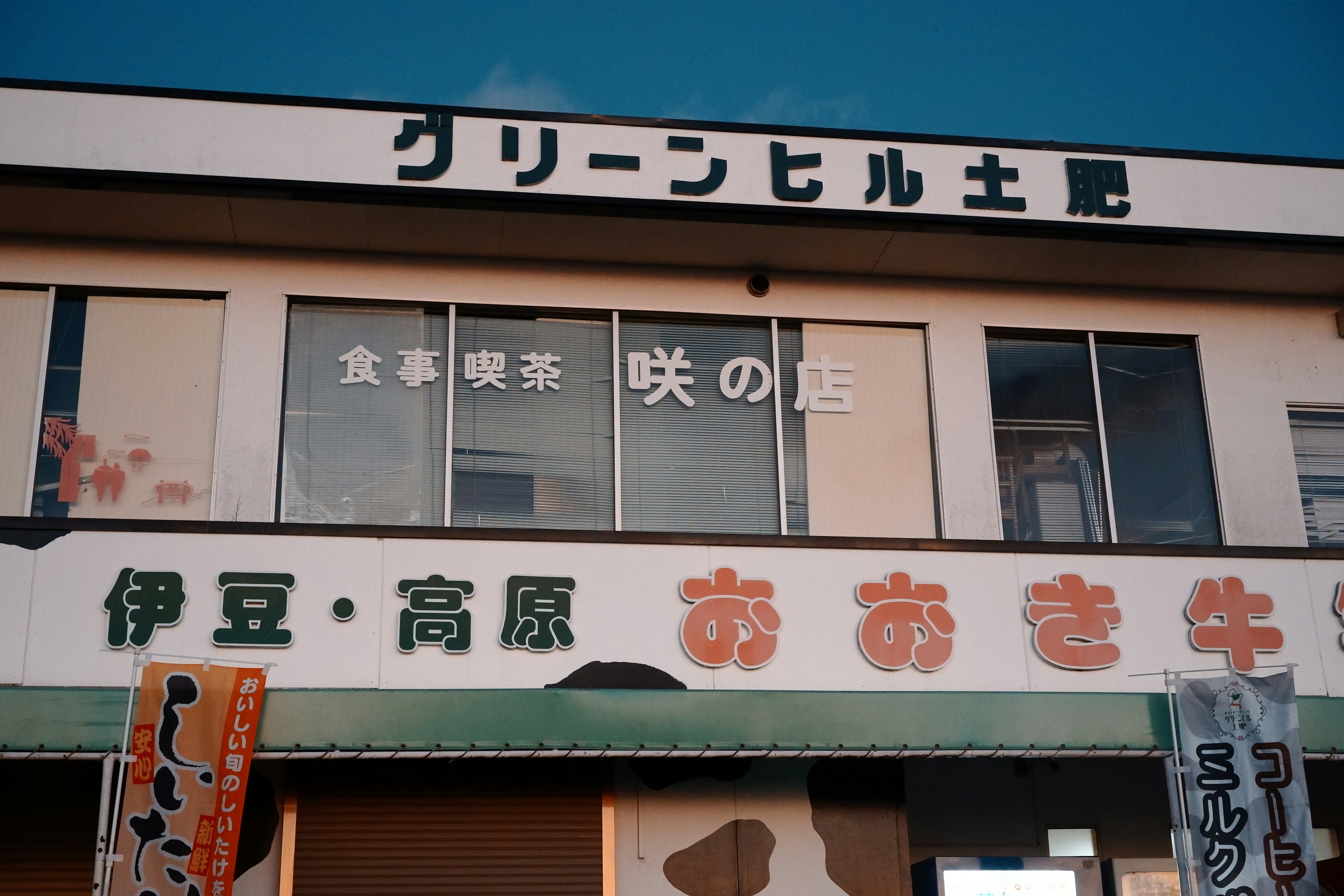 Facade of Green Hill Building featuring a sign and dining establishment