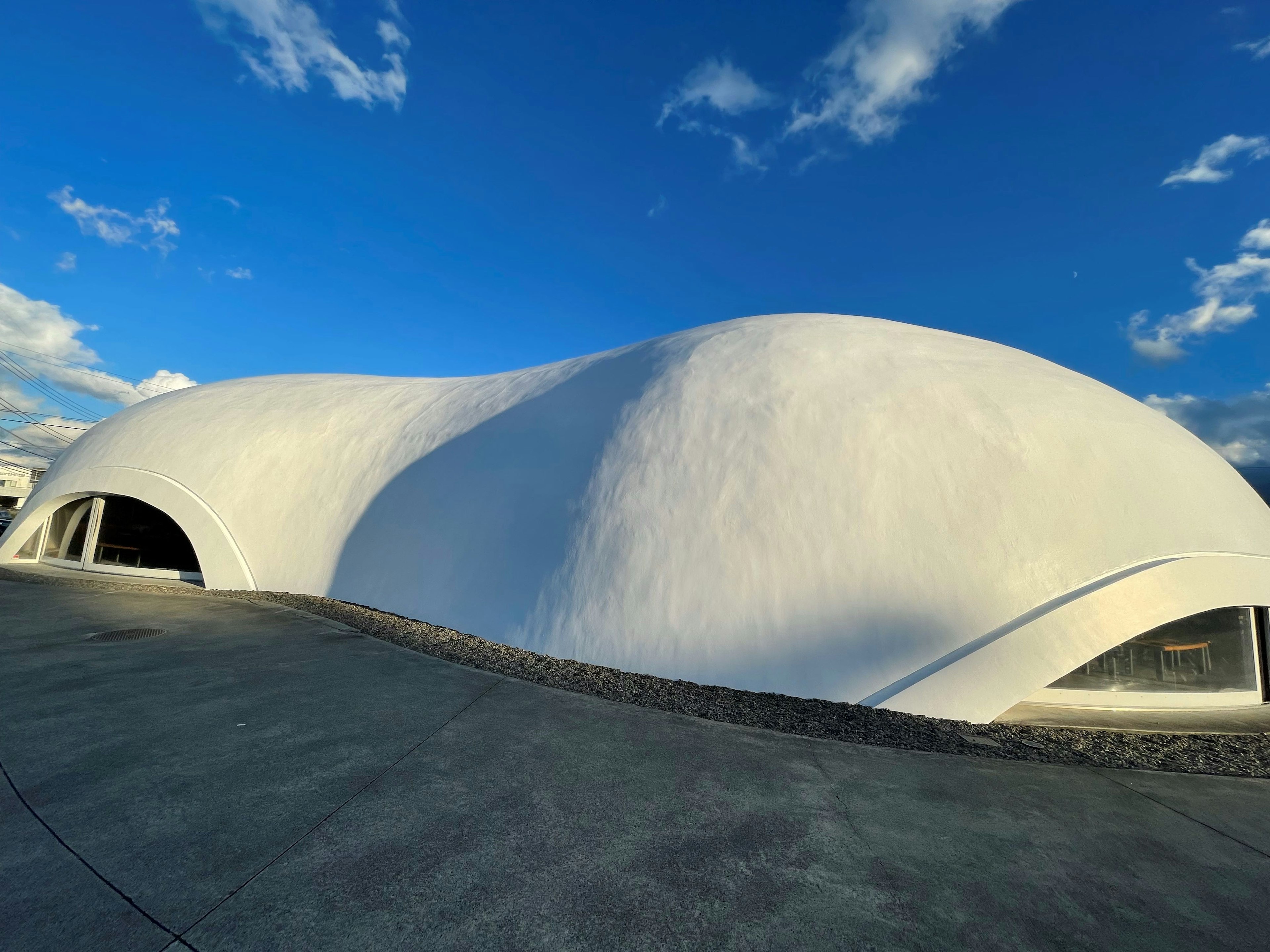 曲線的な白い建物が青空の下にある風景