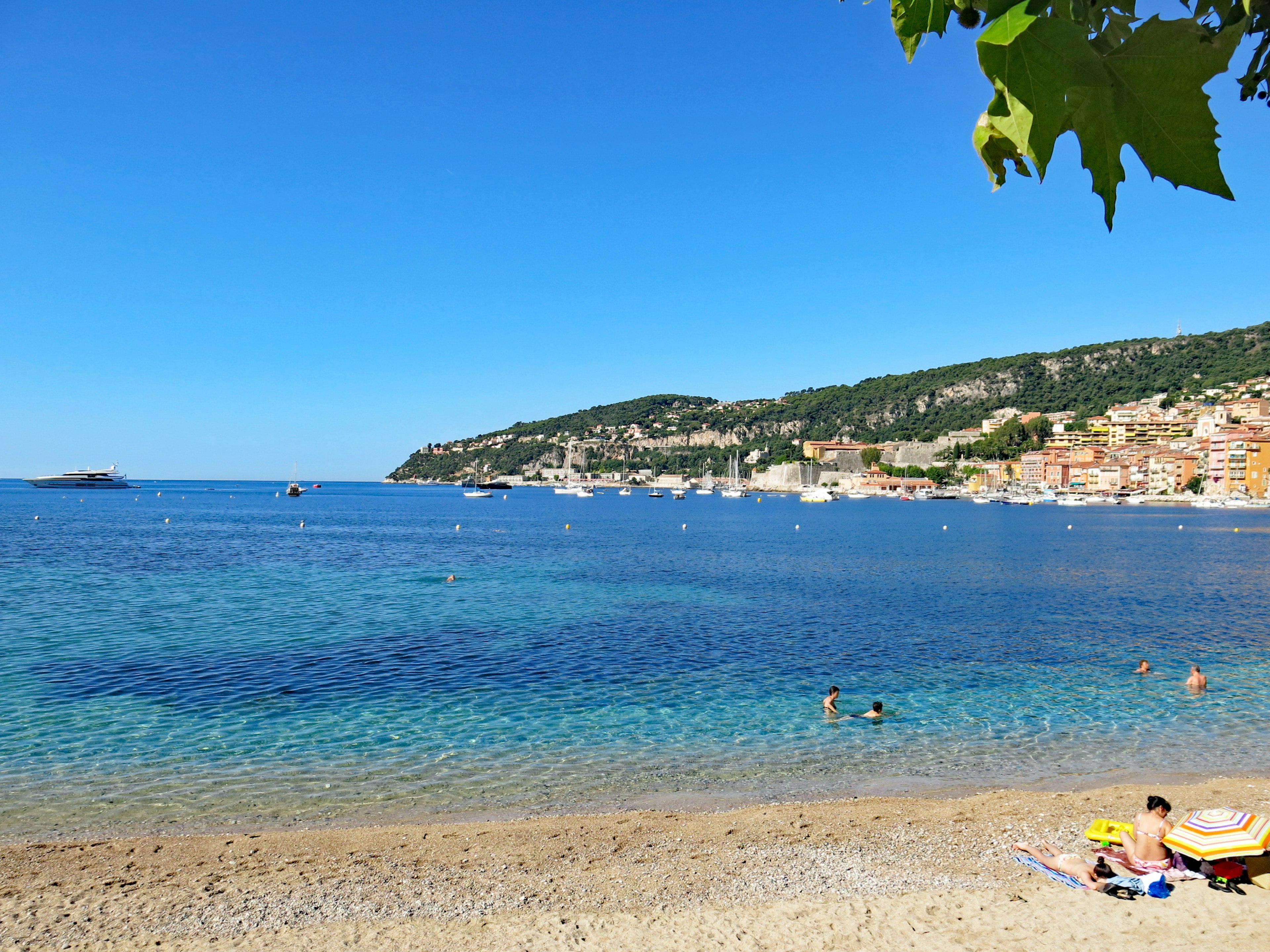 A scenic beach with clear blue water and people enjoying the sun