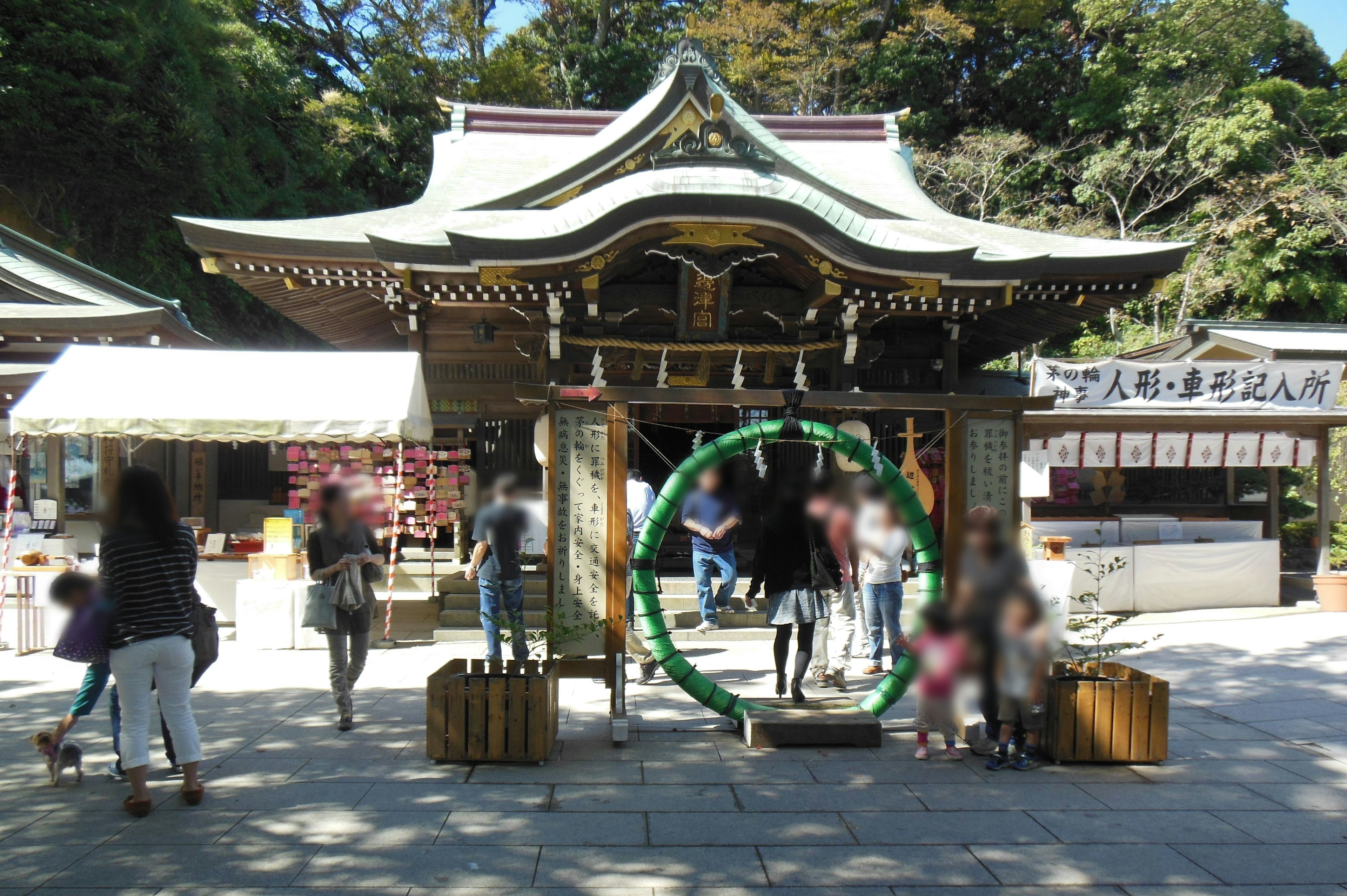 神社の入口にある緑の輪と賑やかな人々の様子