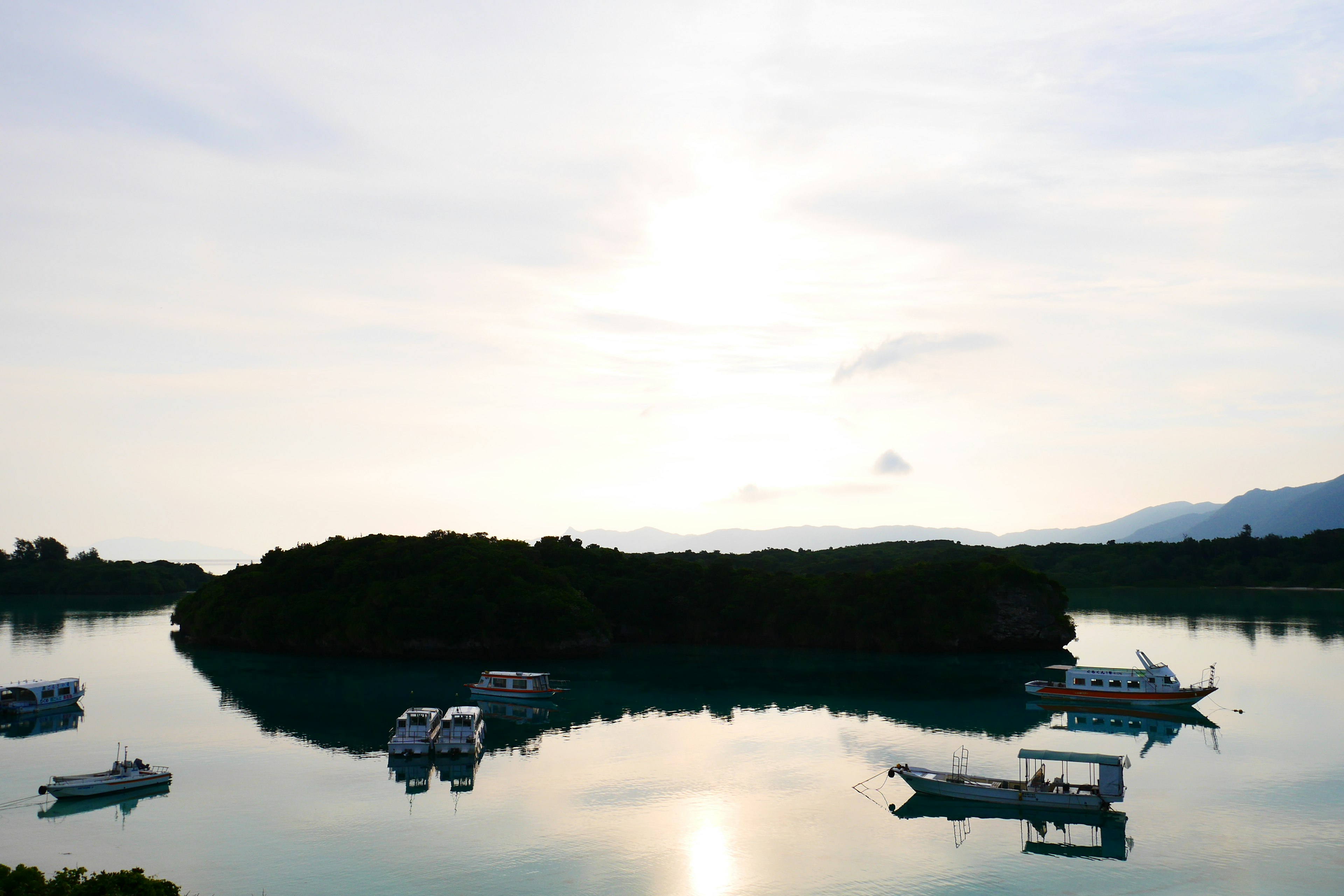 Serene landscape with small boats floating on calm water and an island