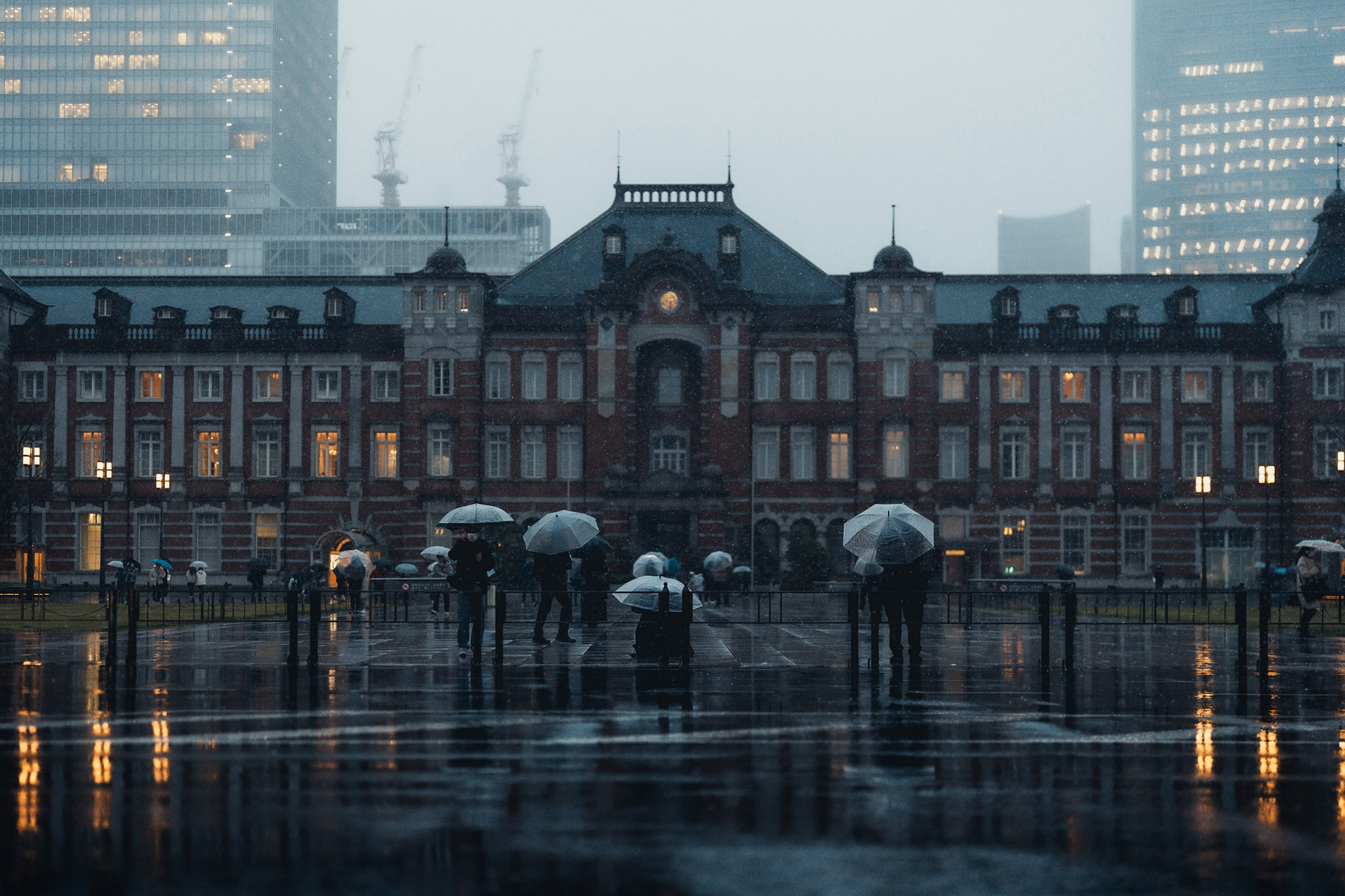 東京駅の歴史的な建物と雨の中の人々