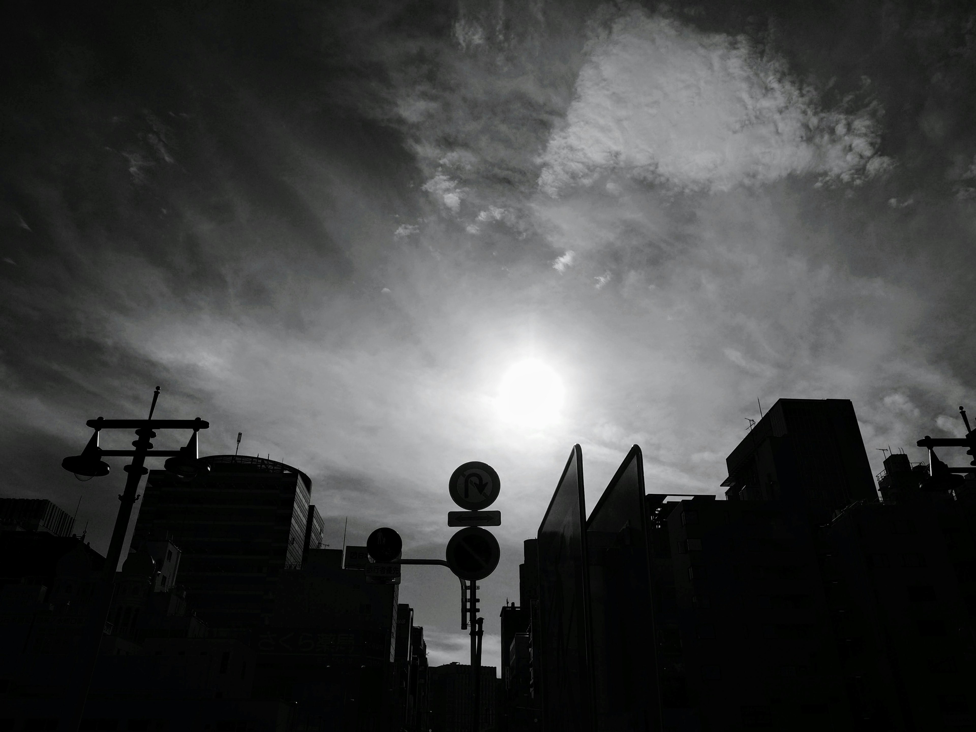 Cielo in bianco e nero con sole splendente e edifici in silhouette