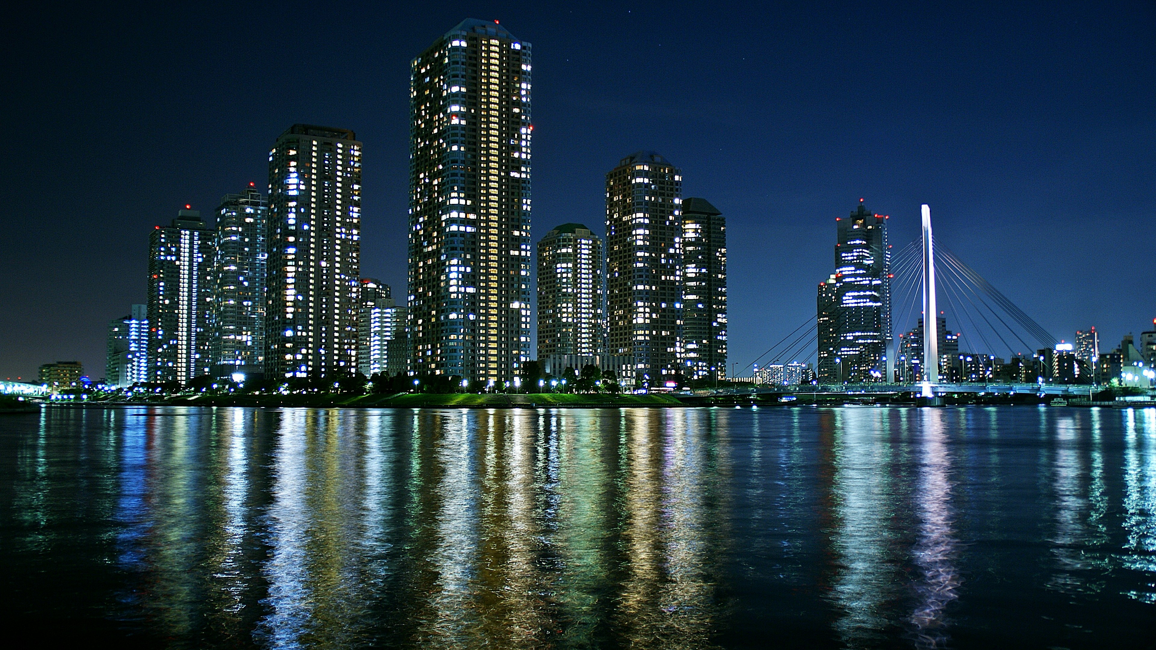 Paisaje urbano nocturno con rascacielos reflejándose en el agua