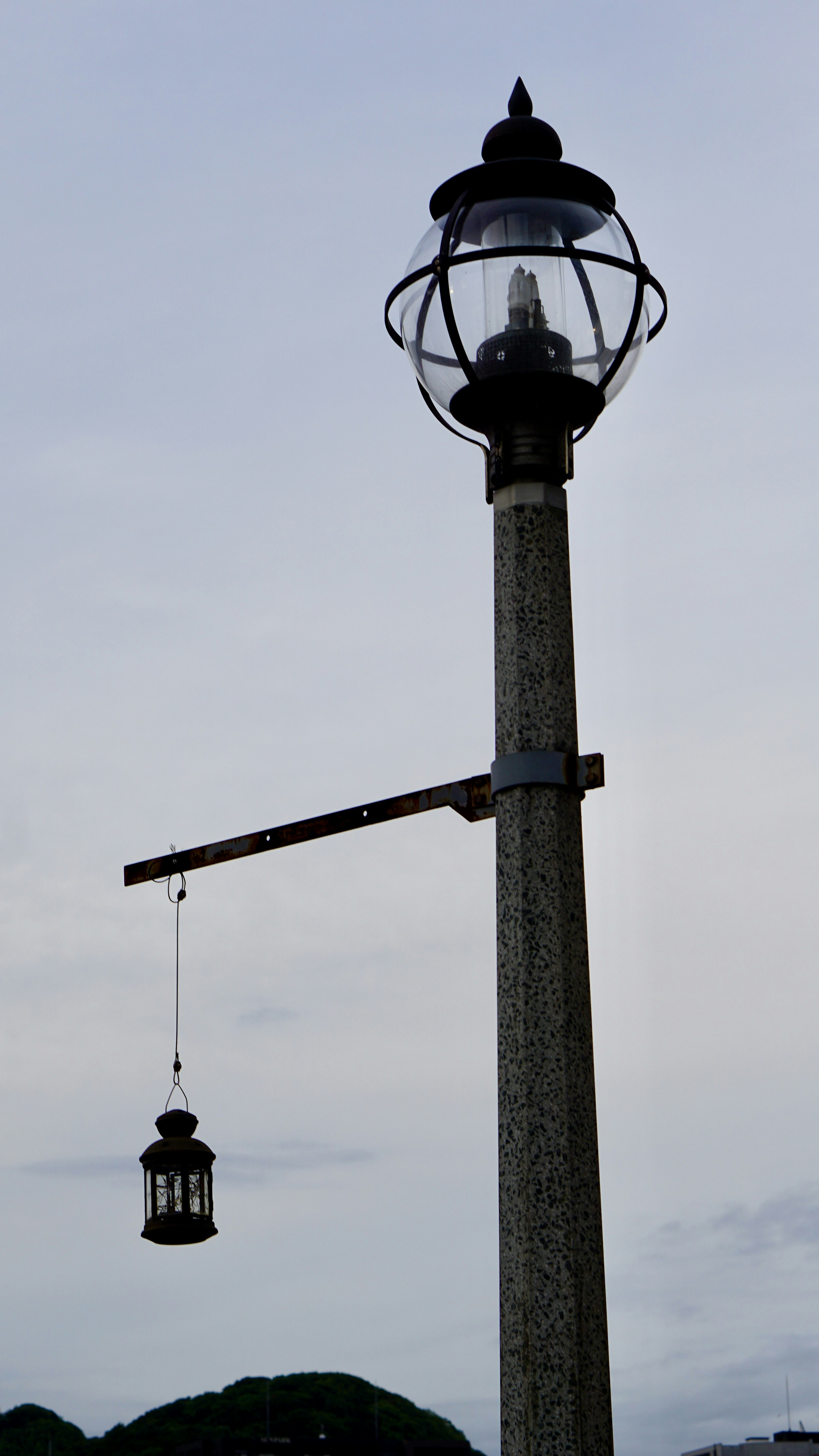 Tiang lampu dengan lentera tergantung di langit abu-abu