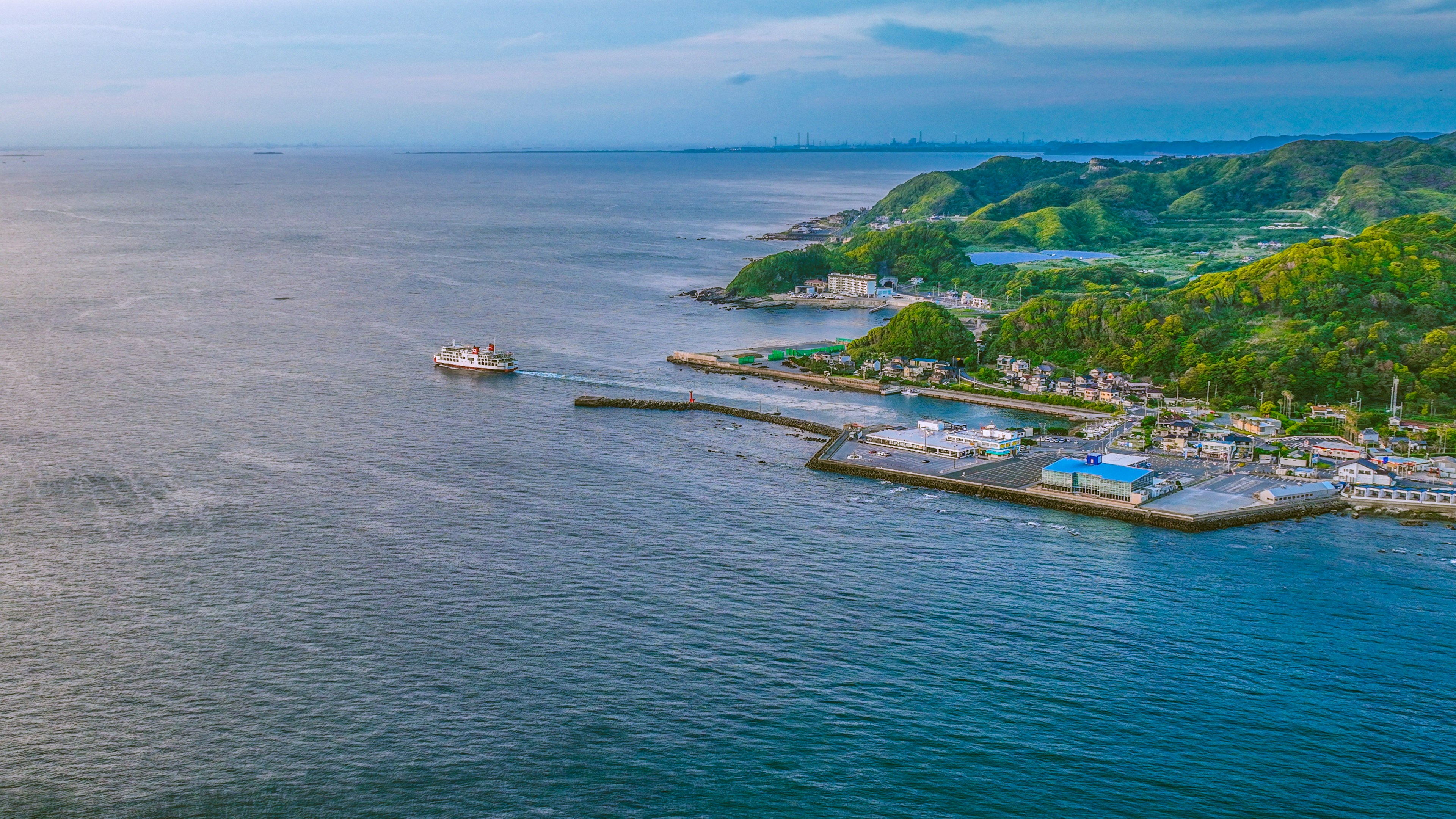 ทิวทัศน์ชายฝั่งที่สวยงามพร้อมท่าเรือที่มีต้นไม้ล้อมรอบและเรือ