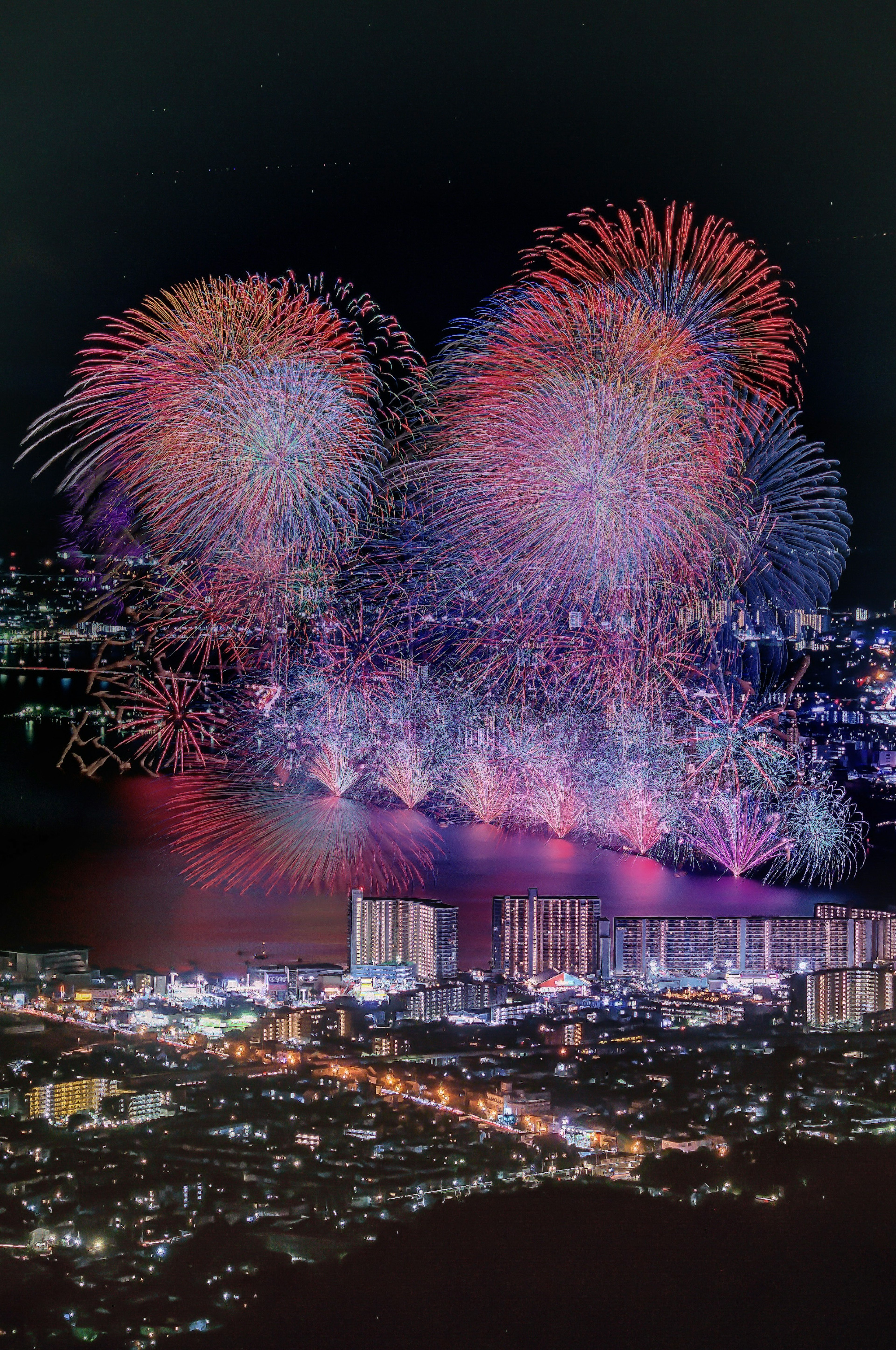 夜空に輝く色とりどりの花火と都市の光景