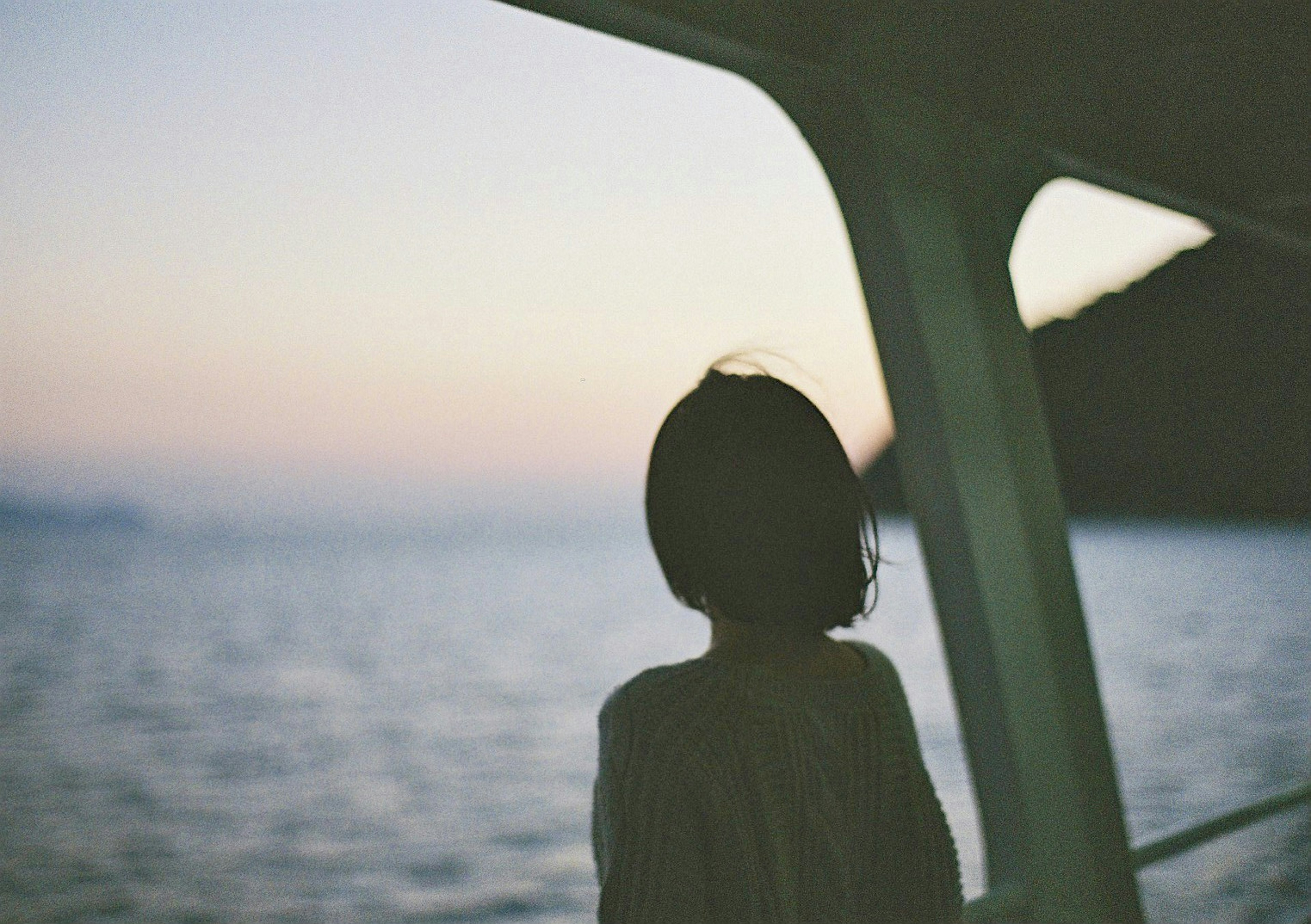 Silhouette einer Frau, die auf das Meer mit Sonnenuntergang im Hintergrund schaut