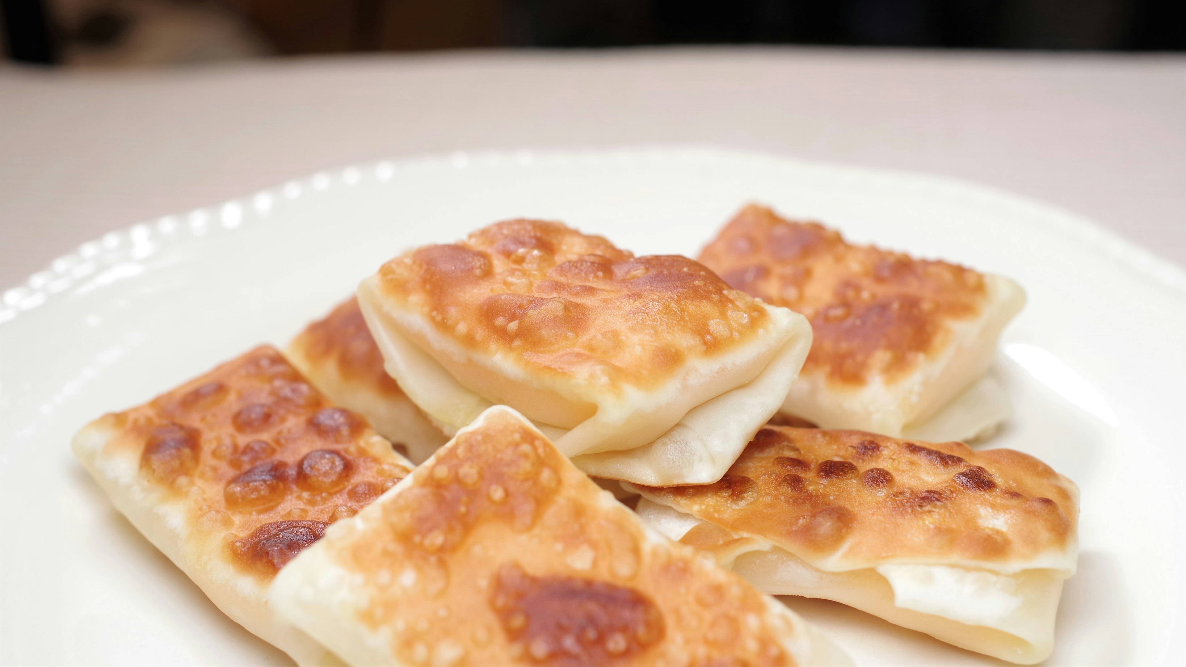 Golden-brown square pastries arranged on a white plate