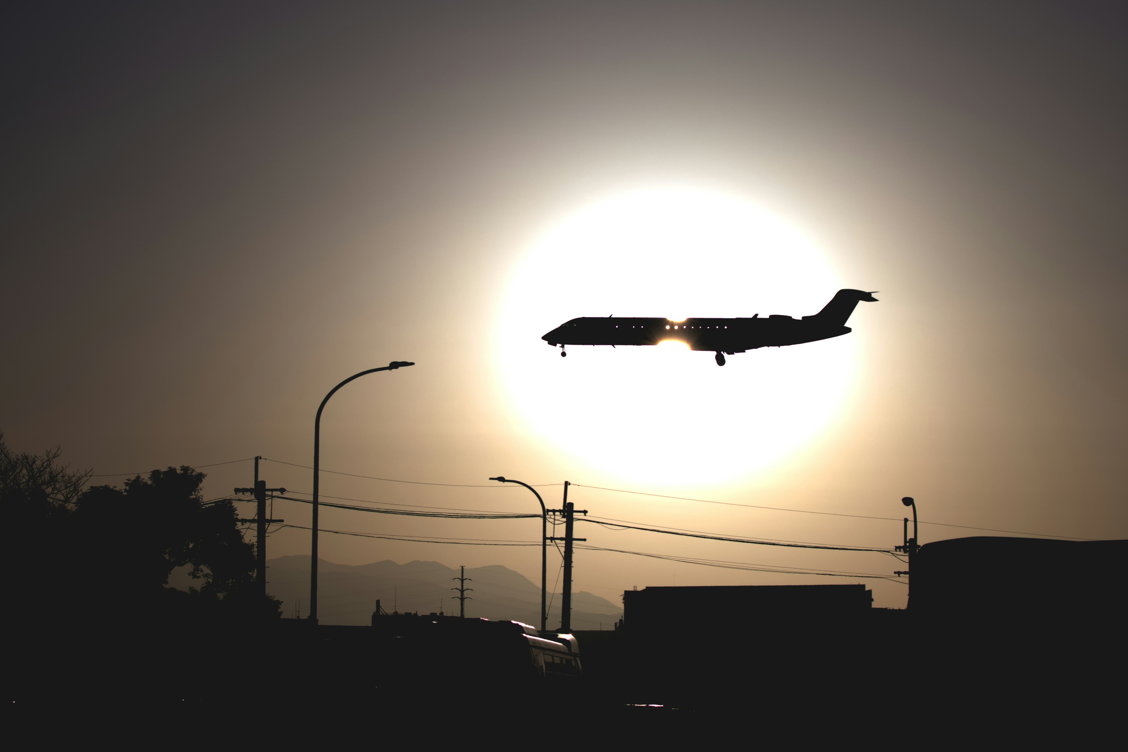 Silhouette of an airplane landing against a sunset