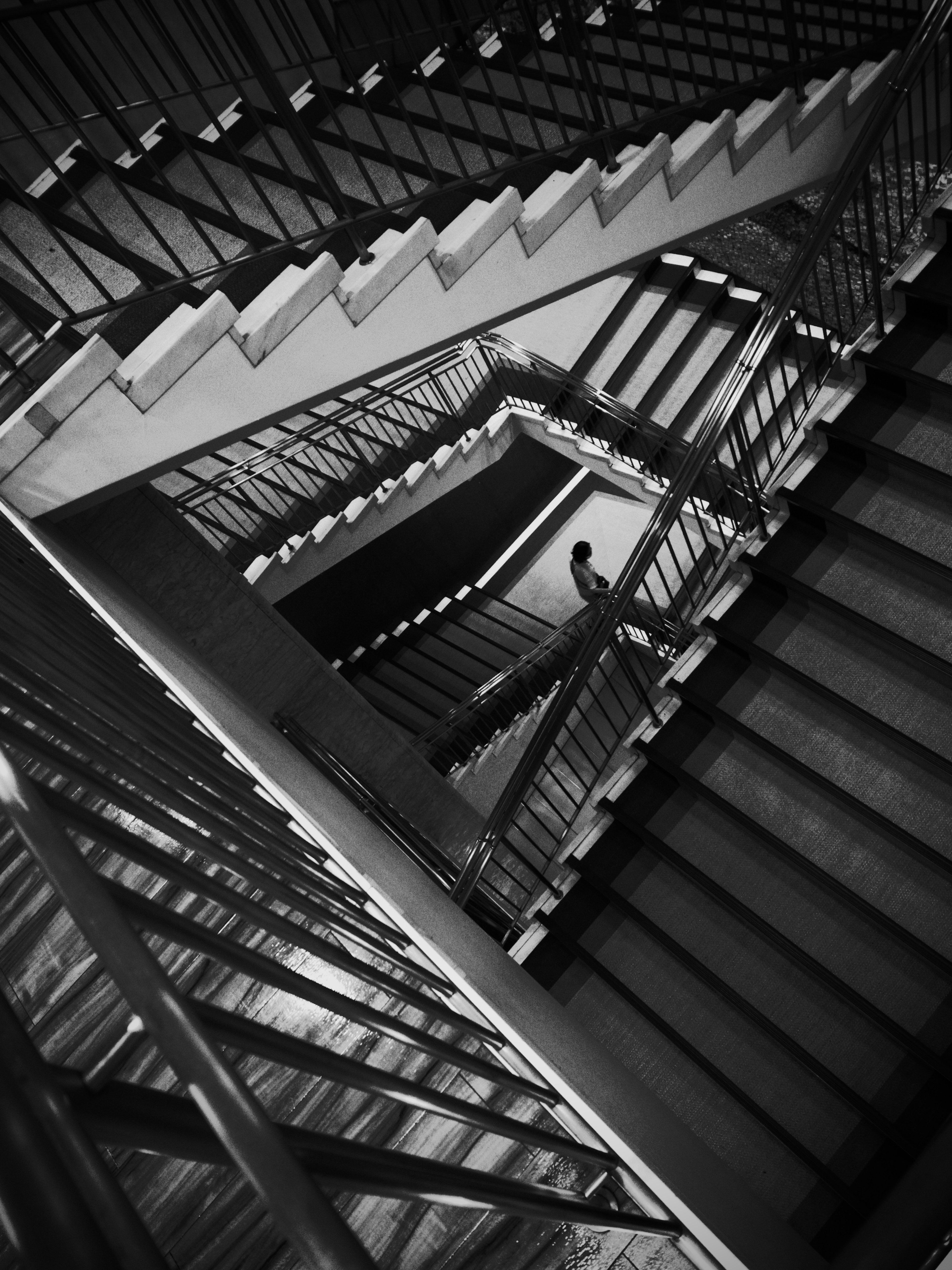 Black and white image of a spiral staircase with a person ascending