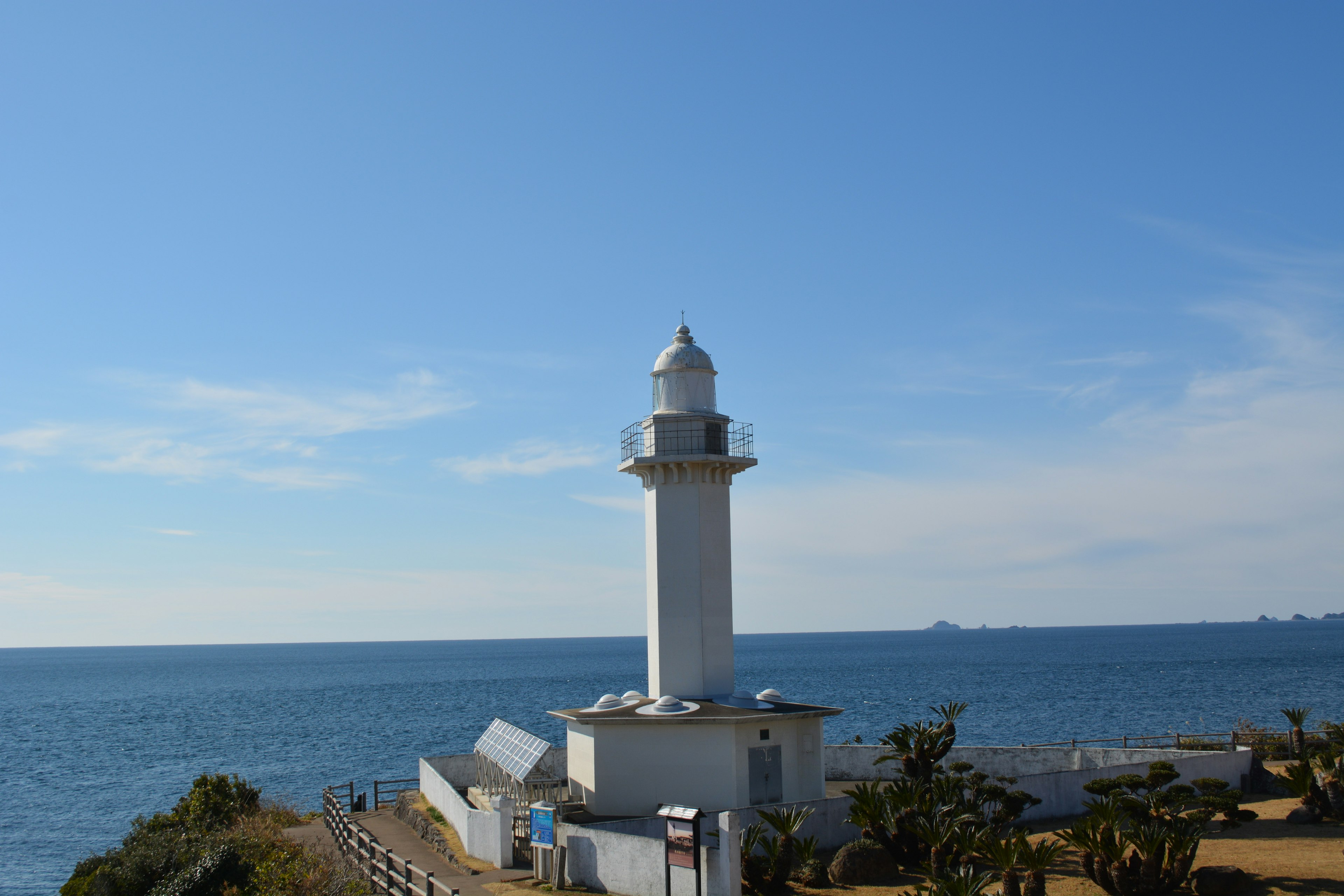 青い海と空の背景に立つ白い灯台