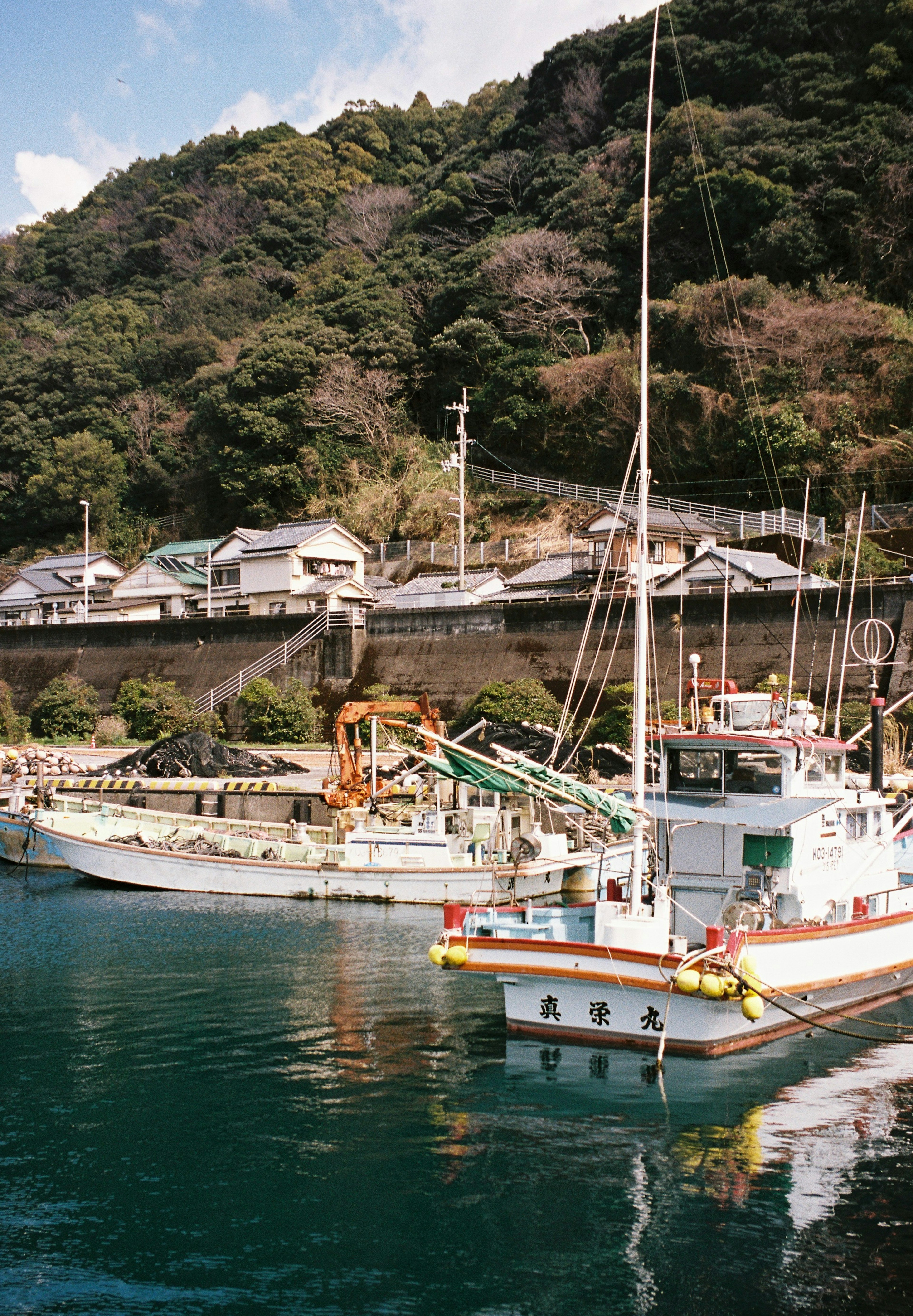 Fishing boats docked in a serene harbor surrounded by lush green hills