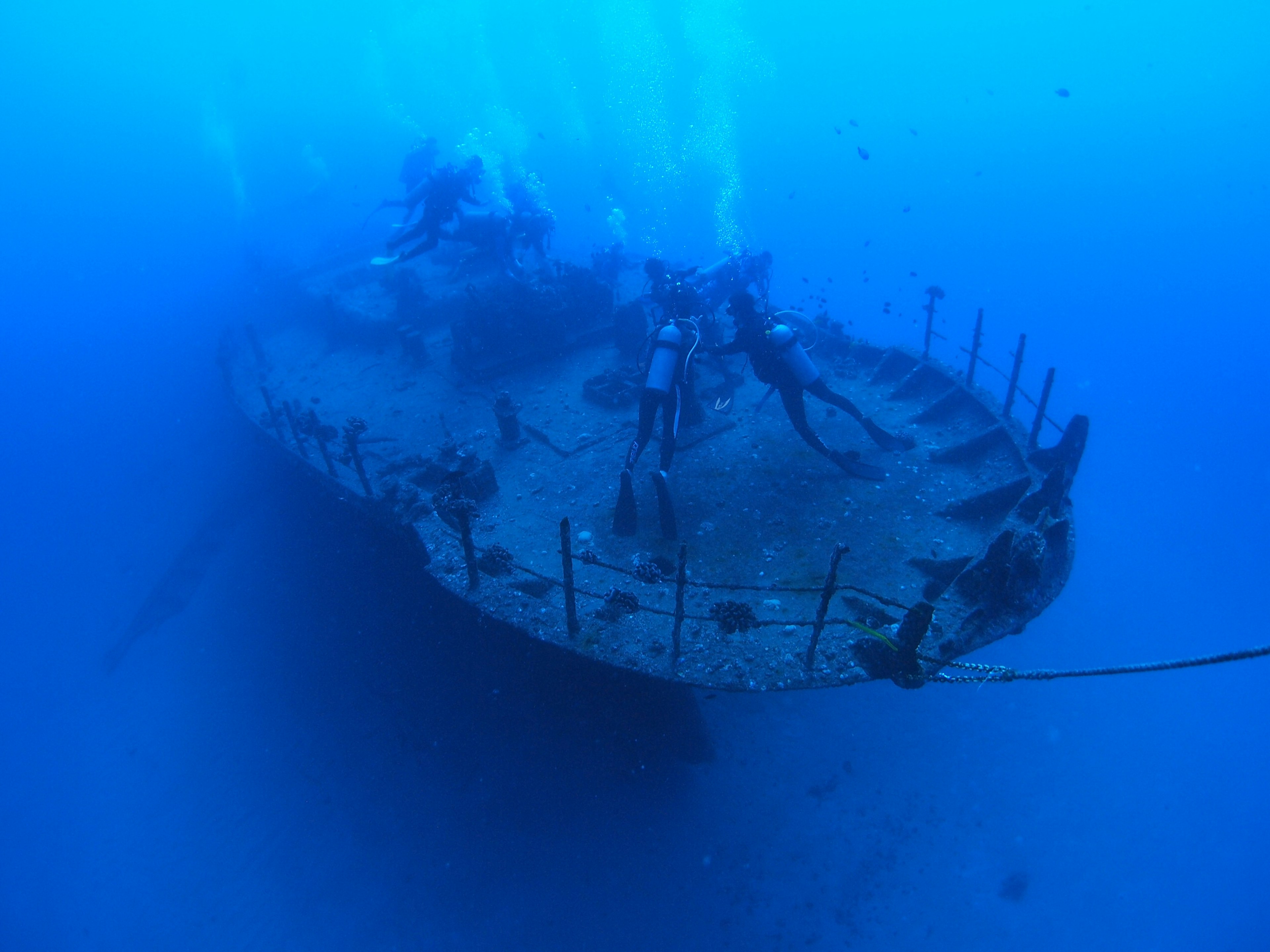 Unterwasserbild eines Schiffswracks umgeben von blauen Ozeanwässern