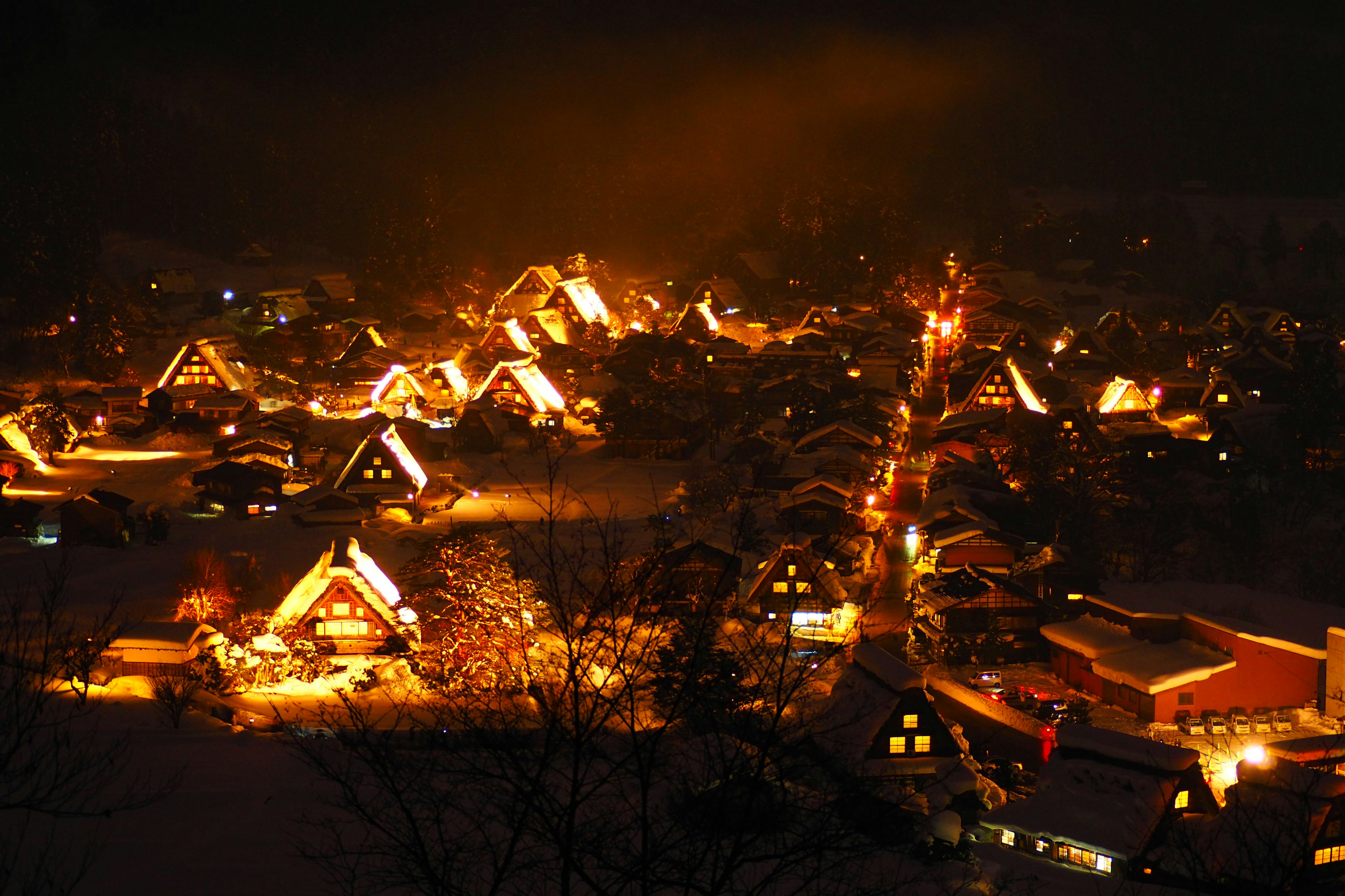 冬の夜に灯りがともる合掌造りの村の景色