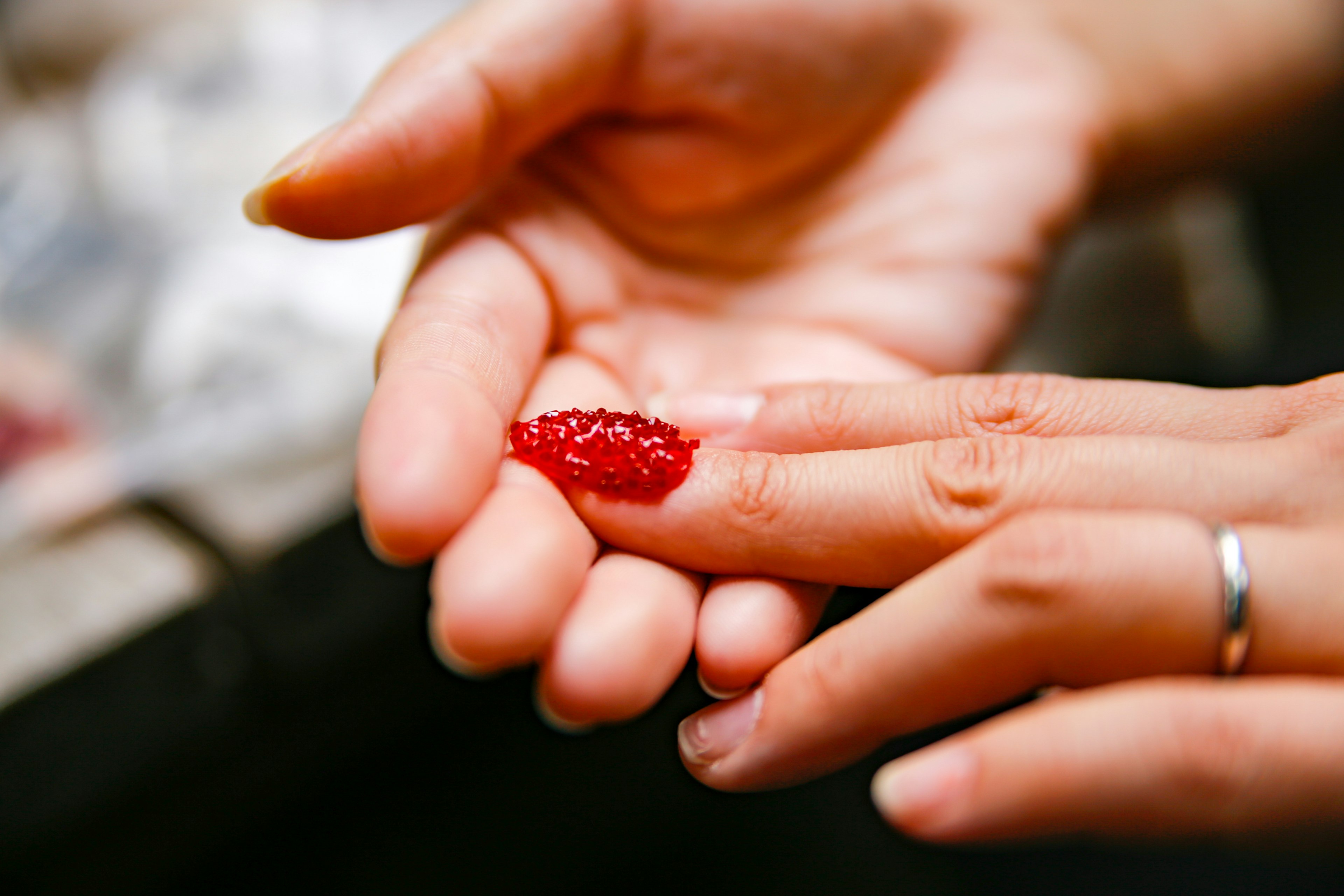 Primer plano de una mano sosteniendo un ingrediente rojo en un dedo