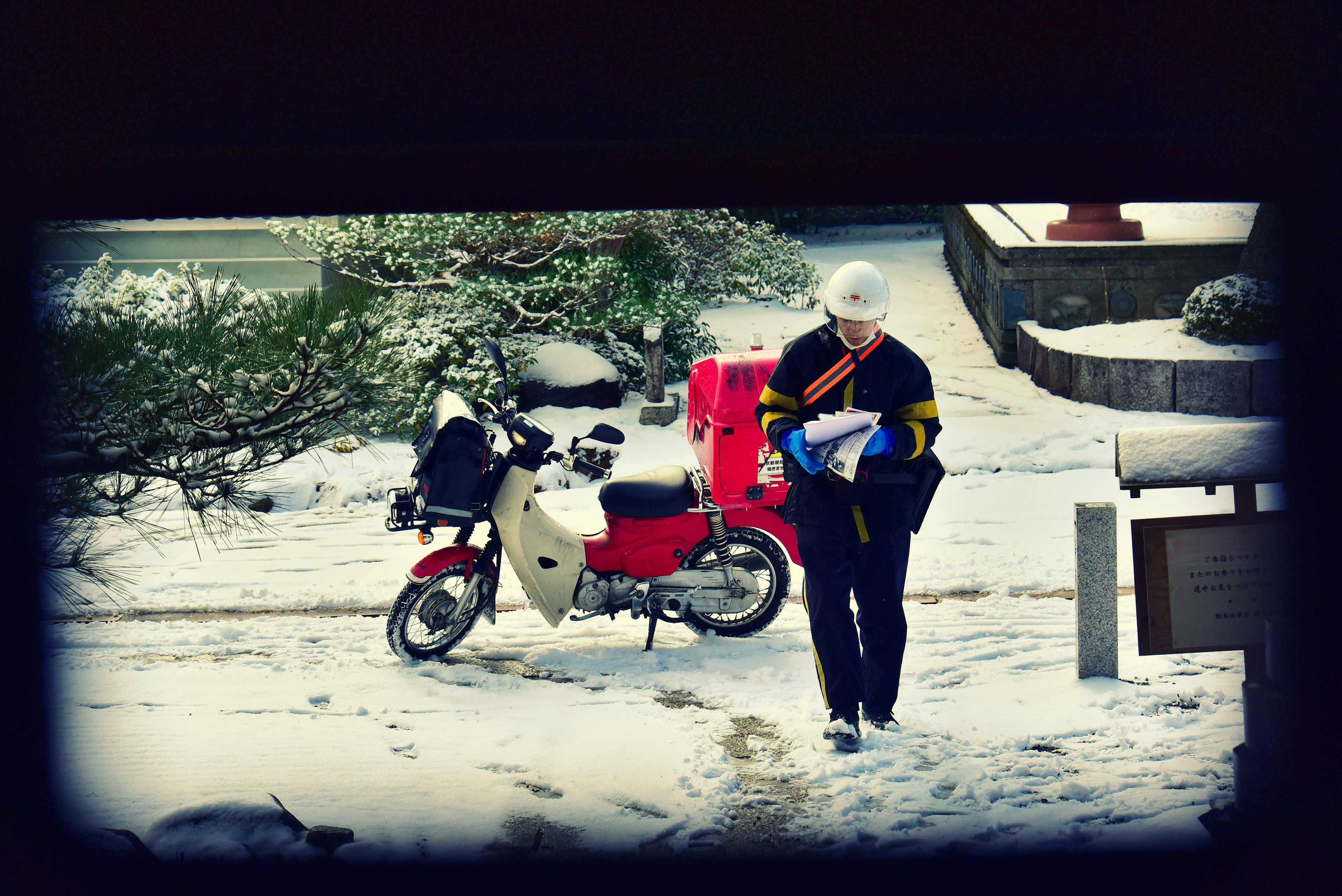 Livreur marchant dans la neige avec une moto rouge