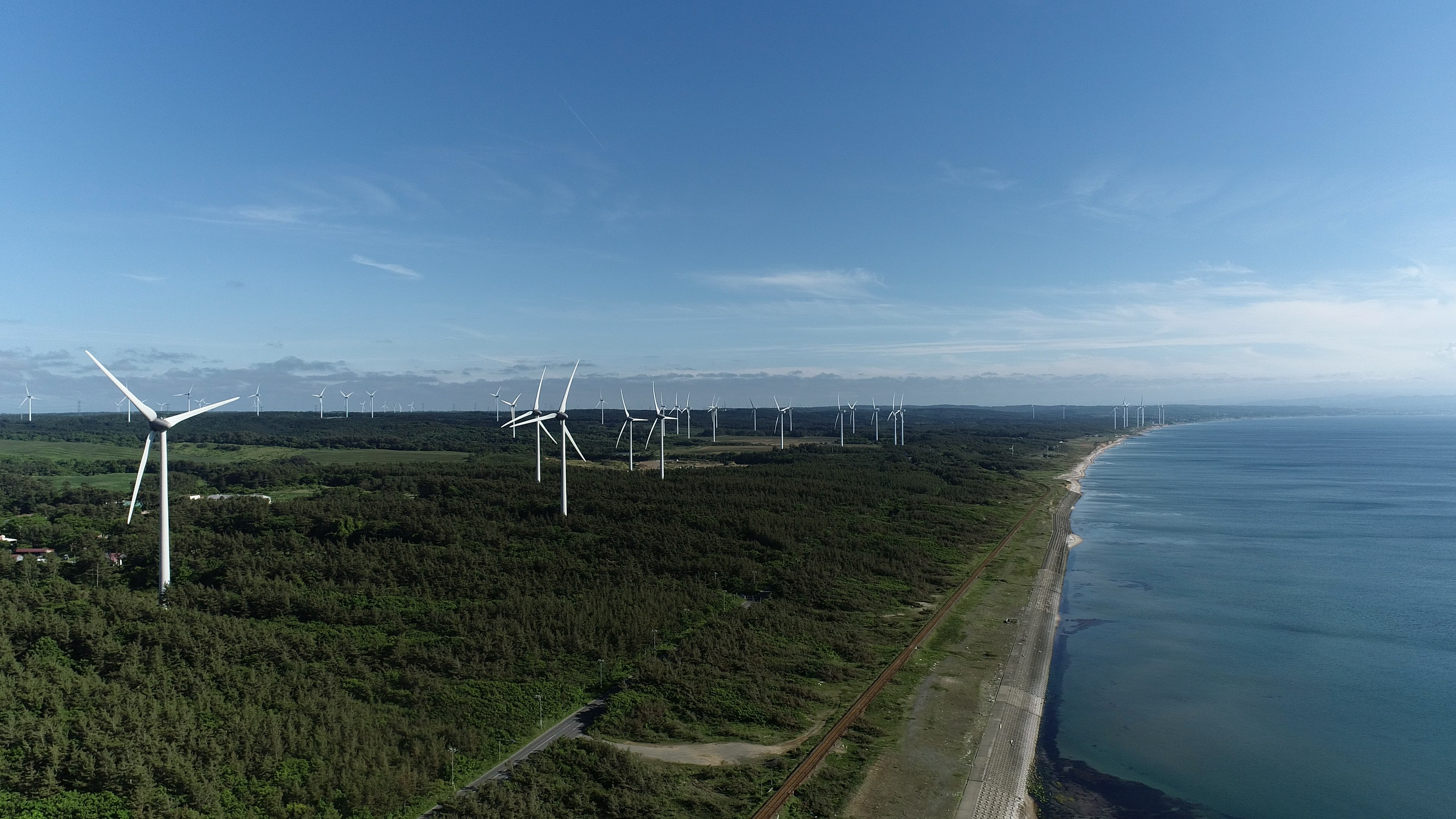 Vista costiera con turbine eoliche e cielo blu chiaro